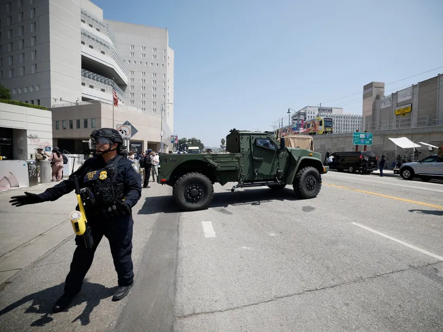 شاحنة تابعة للحرس الوطني الأميركي تتحرك بينما يقف أفراد من قوات الأمن لحراستها بالقرب من مبنى إدوارد ر. رويبال الفيدرالي، مدينة لوس أنجلوس، كاليفورنيا، الولايات المتحدة. 10 يونيو 2025 - REUTERS
