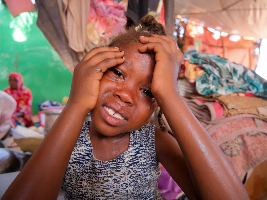 طفلة سودانية تبكي بعد سماع قصة والدتها بعد أن فرّت العائلة من مدينة الفاشر الممزقة بالحرب مع تدهور الوضع الإنساني وسط الصراع المستمر بين قوات الدعم السريع والجيش السوداني، في مخيم للنازحين في الدبة، السودان. 6 سبتمبر 2025. - Reuters