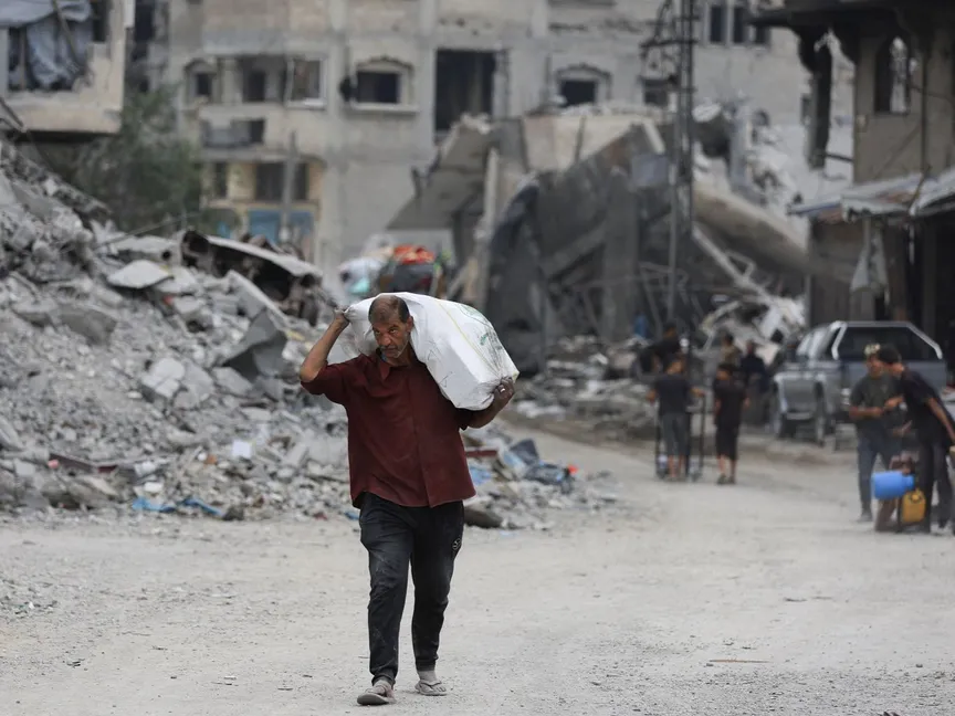 فلسطيني يحمل مساعدات غذائية في مدينة غزة عقب الانسحاب الإسرائيلي وفق اتفاق وقف إطلاق النار. 12 أكتوبر 2025 - REUTERS