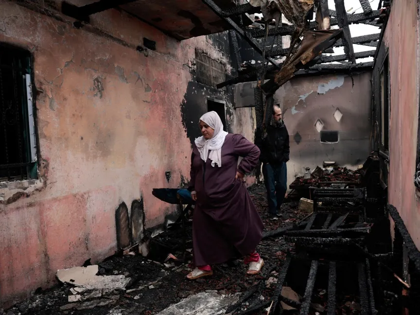 فلسطينيان يتفقدان منزلاً متضرراً بعد أن أضرم فيه مستوطنون إسرائيليون النيران في قرية الفندقومية قرب جنين بالضفة الغربية المحتلة. 22 مارس 2026 - REUTERS