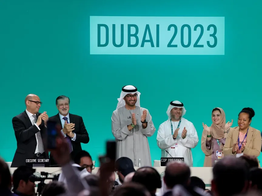 رئيس مؤتمر الأطراف 28 سلطان أحمد الجابر يصفق بين مسؤولين آخرين قبل الجلسة العامة خلال قمة الأمم المتحدة للمناخ في دبي في 13 ديسمبر 2023 - AFP
