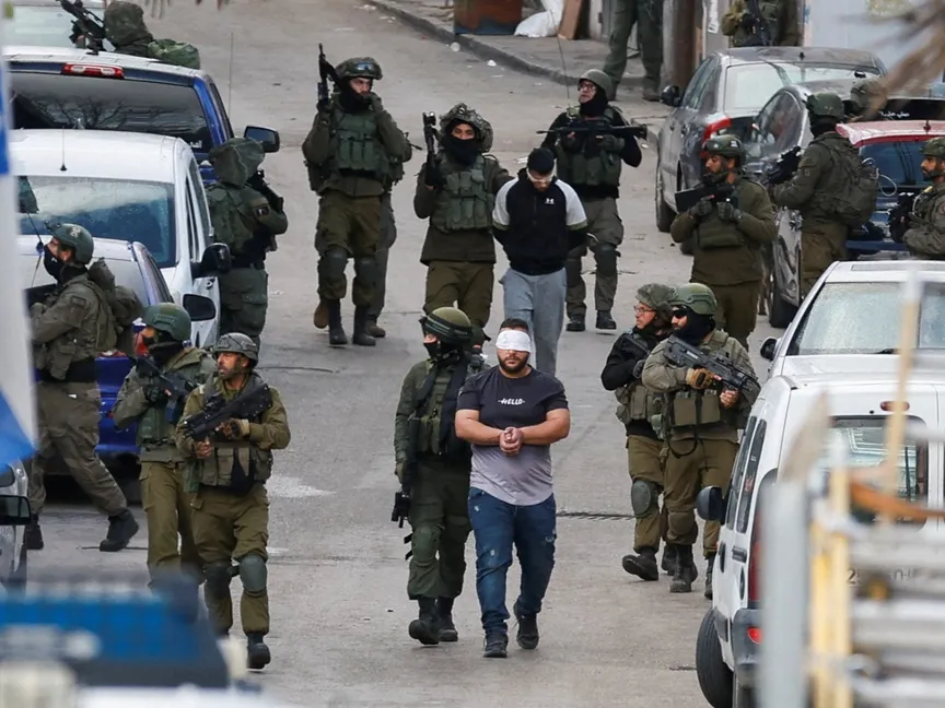 جنود إسرائيليون يحتجزون فلسطينيين خلال مداهمة في رام الله بالضفة الغربية التي تحتلها إسرائيل. 4 مارس 2024 - REUTERS
