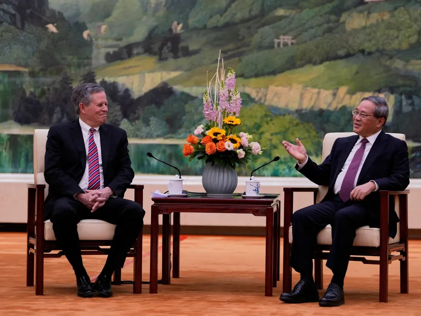 رئيس الوزراء الصيني لي تشيانج، خلال لقائه السيناتور الأميركي ستيف داينس بقاعة الشعب الكبرى في بكين، الصين، الأحد 23 مارس 2025 - REUTERS