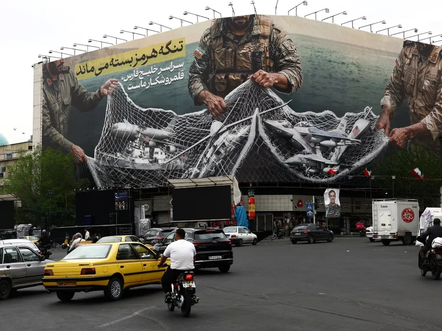 سيارات تسير بالقرب من لوحة إعلانية مناهضة للولايات المتحدة على مبنى في طهران. 12 أبريل 2026 - Reuters