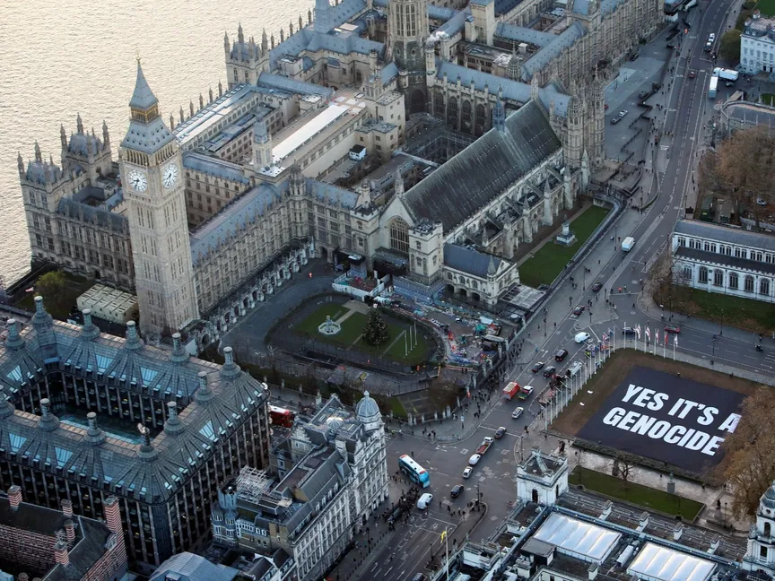 لافتة بالقرب من البرلمان البريطاني مكتوب عليها "نعم إنها الإبادة" في لندن. 4 ديسمبر 2024 - Reuters