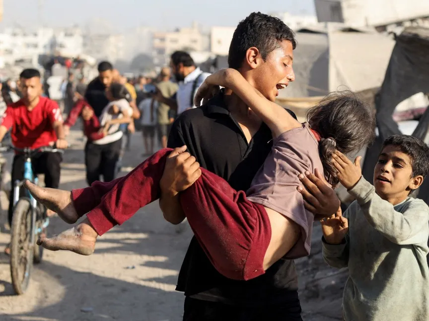 فلسطيني يحمل طفلة مصابة عقب ضربة إسرائيلية استهدفت نادي الجزيرة حيث كان النازحون قد احتموا، في مدينة غزة. 7 سبتمبر 2025 - Reuters