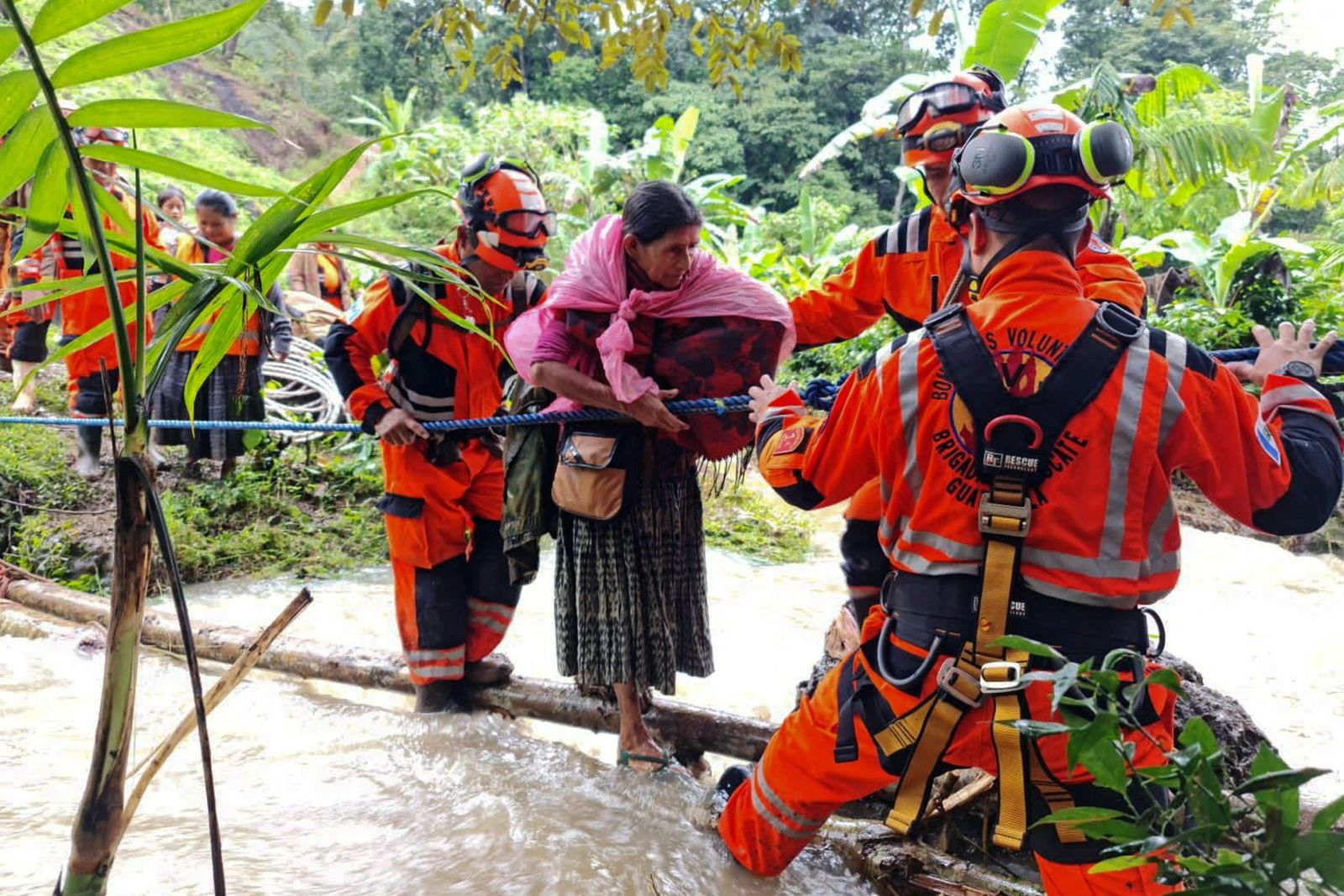 Handout picture released by Volunteer Firefighters showing their rescue patrol evacuating people after being trapped in a landslide, following the passage of Tropical Storm Julia, at Queja village, in San Cristobal Verapaz, Guatemala, on October 10, 2022. - Tropical Depression Julia dissipated Monday in western Guatemala, near Mexico, after leaving at least 11 dead and eight missing in northern Central America, as well as flooding and property damage, according to official reports. (Photo by Handout / BOMBEROS VOLUNTARIOS / AFP) / RESTRICTED TO EDITORIAL USE - MANDATORY CREDIT 