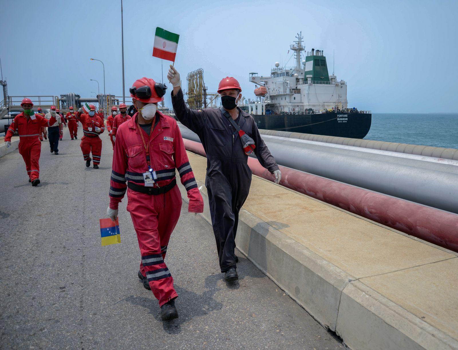 عامل بشركة النفط الوطنية الفنزويلية يرفع علم إيران في ميناء إل باليتو، في فنزويلا - AFP