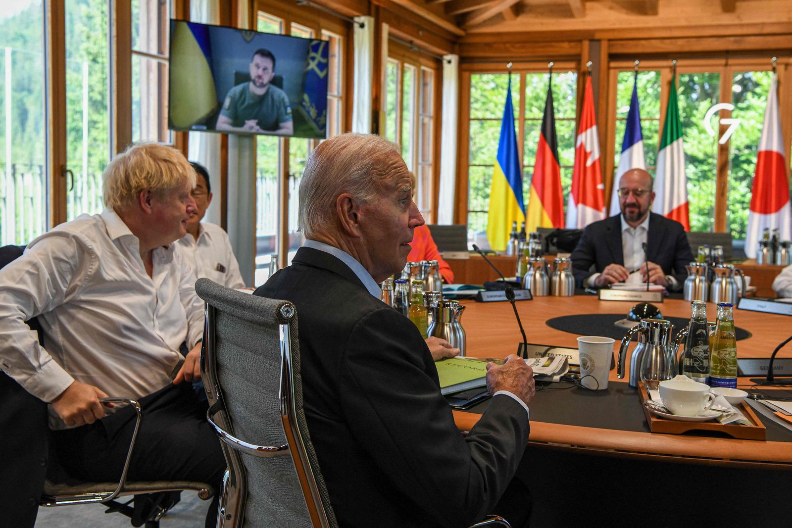 (L-R) Britain's Prime Minister Boris Johnson, Japan's Prime Minister Fumio Kishida, US President Joe Biden and European Council President Charles Michel have taken seat at a round table as Ukraine's President Volodymyr Zelensky (on the screen) addresses G7 leaders via video link during their working session on June 27, 2022 at Elmau Castle, southern Germany, where the German Chancellor hosts a summit of the Group of Seven rich nations (G7). - G7 leaders are under pressure to hold fast to climate pledges when they meet in Bavaria from June 26 to 28, as Russia's energy cuts trigger a dash back to planet-heating fossil fuels. (Photo by Kenny Holston / POOL / AFP) - AFP