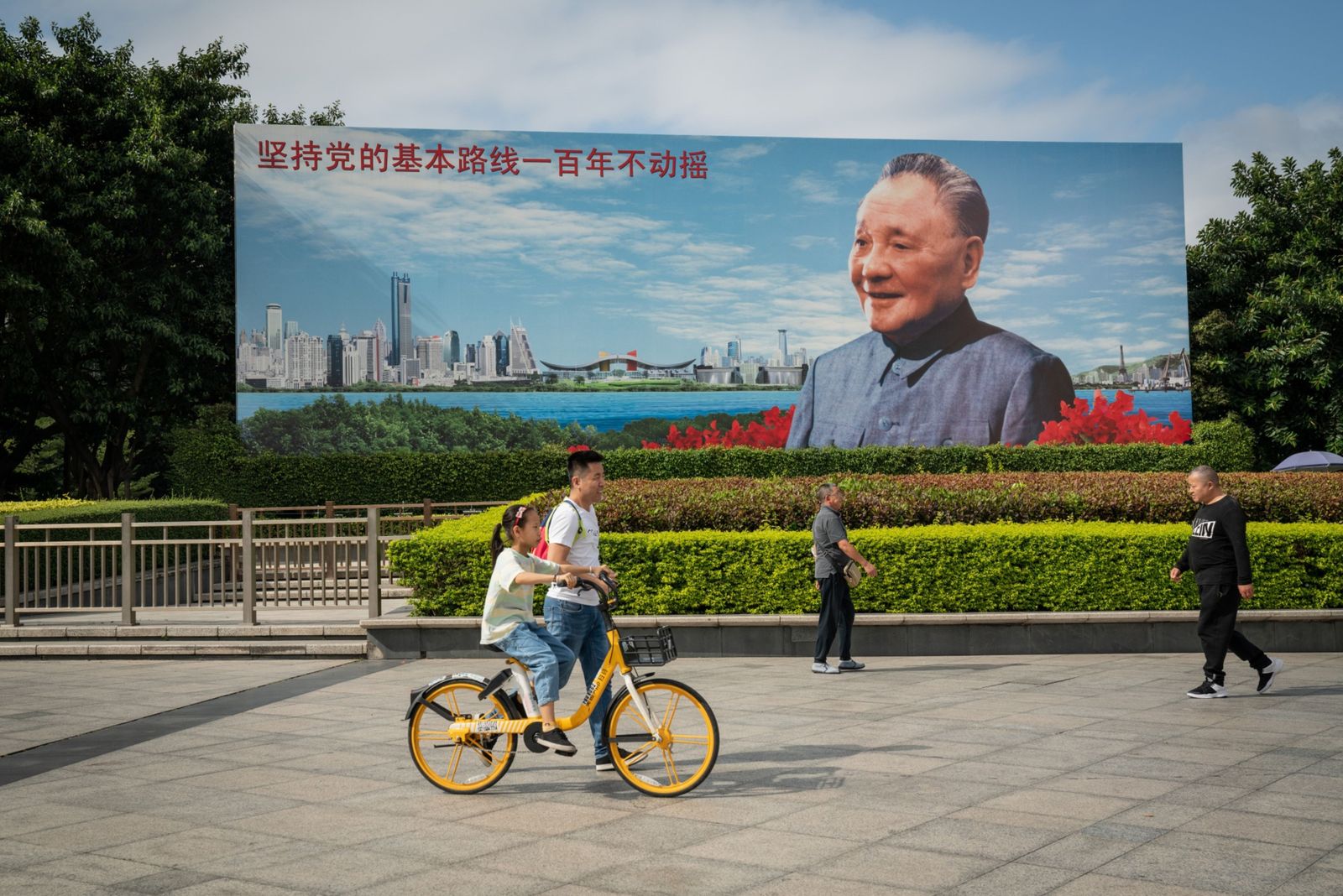 يسيرون في ساحة أمام صورة للزعيم الصيني الراحل دينغ شياو بينغ في مدينة شينزن - 21 نوفمبر 2020 - Bloomberg