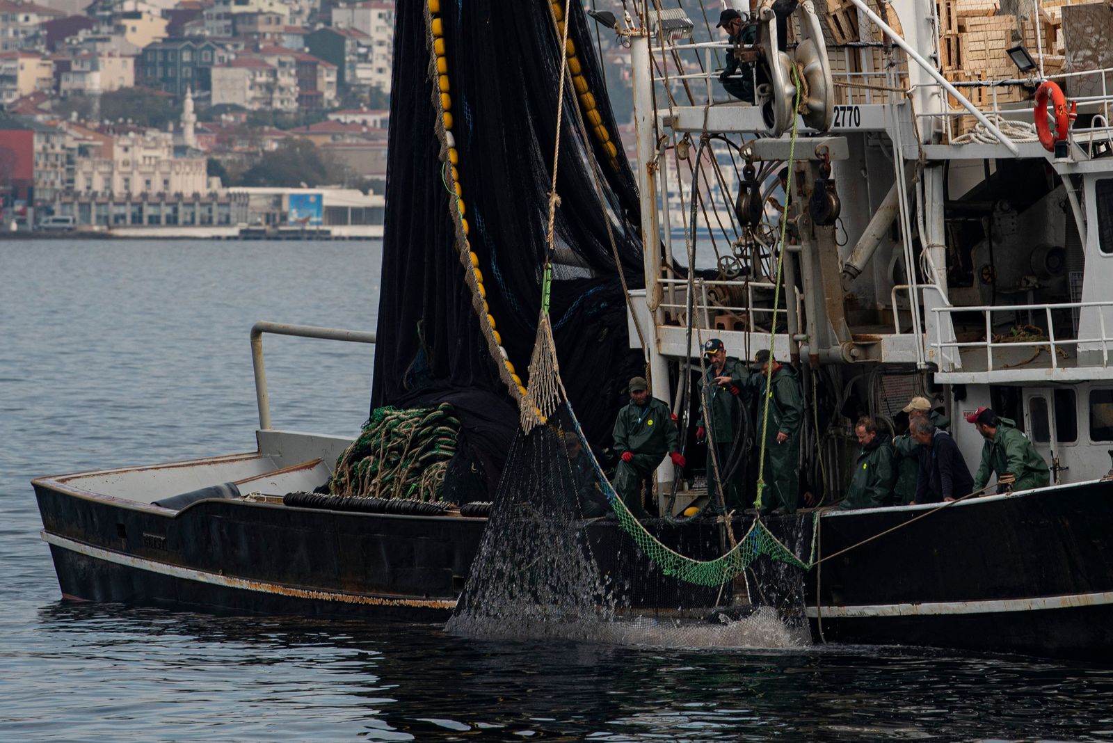 A fishing boat lays its nets in the Marmara sea off the cost of Istanbul, on November 6, 2022. - It is high season for the popular variety of tuna, with shoals teeming through the Bosphorus on their way from the Black Sea to the Mediterranean. But pulled taut across the strait are fishing nets more than a kilometre (3,280 feet) long. Anglers who cram shoulder to shoulder along the banks say the nets leave them with little chance, and the fish with even less. (Photo by Yasin AKGUL / AFP) - AFP