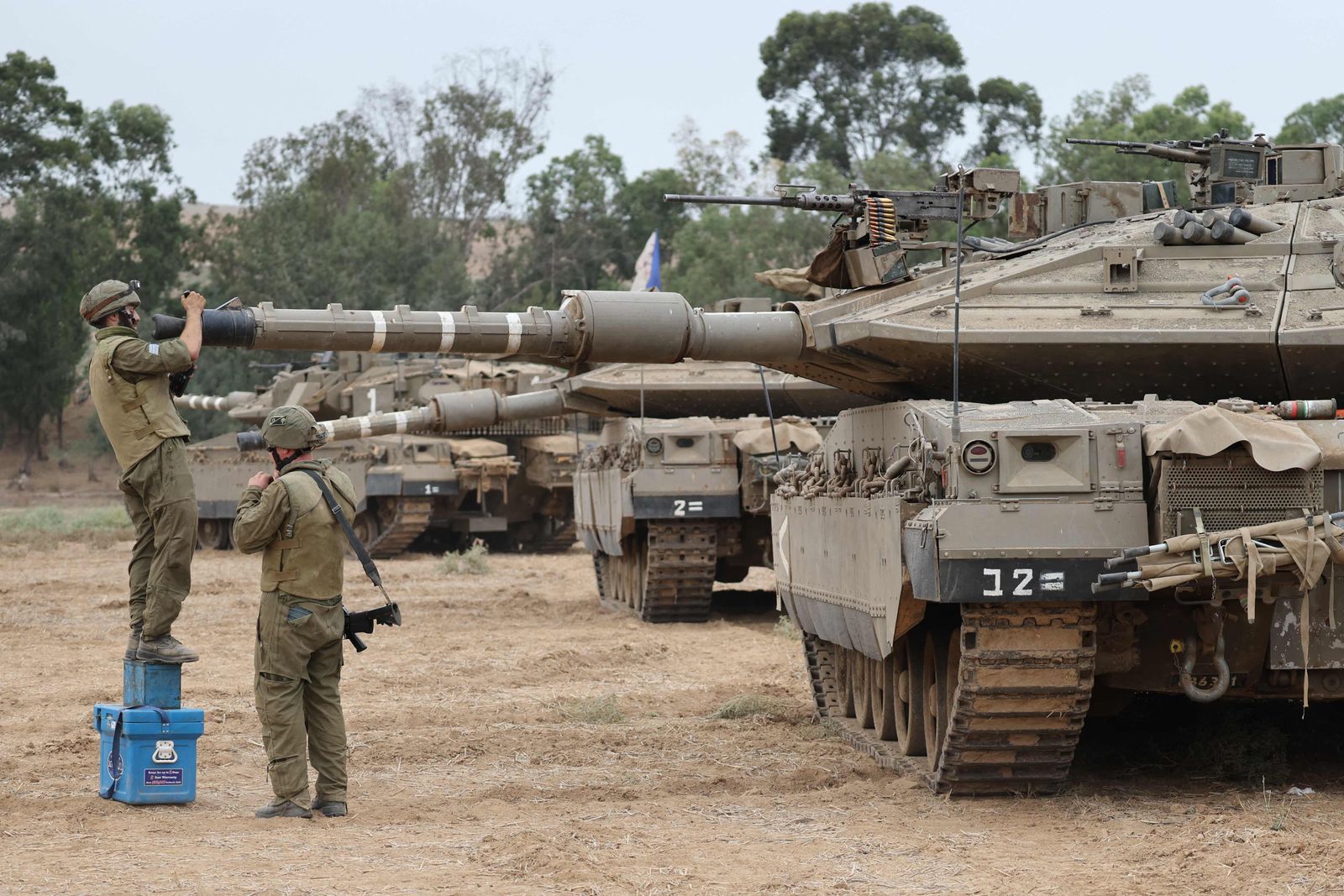 Israeli army soldiers are positioned with their Merkava tanks near the border with the Gaza Strip in southern Israel on October 9, 2023. Israel continued to battle Hamas fighters on October 9 and massed tens of thousands of troops and heavy armour around the Gaza Strip after vowing a massive blow over the Palestinian militants' surprise attack. (Photo by JACK GUEZ / AFP)