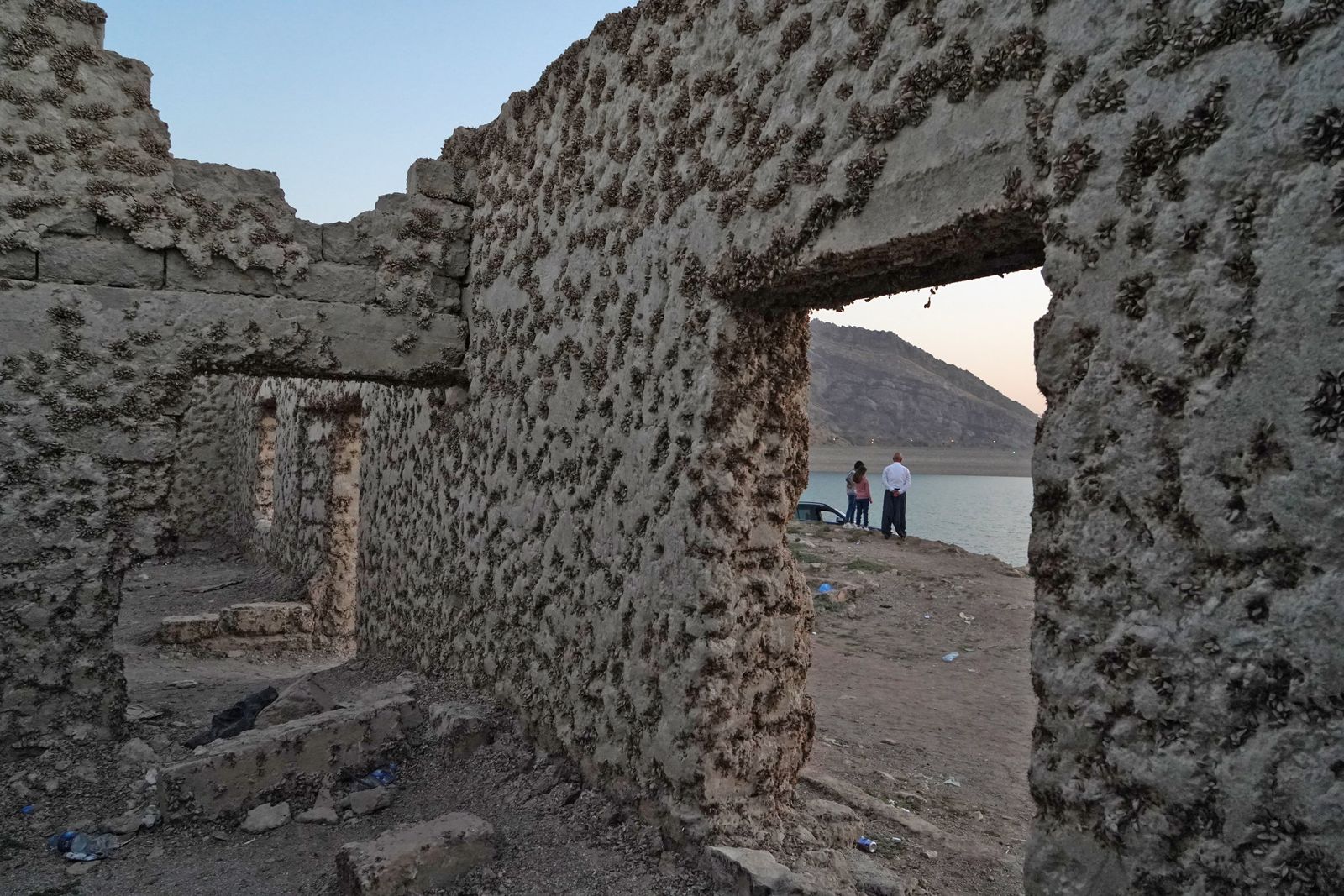 يزور الناس بقايا قرية غاري كسروكة المغمورة بالمياه المهجورة منذ 36 عامًا، والتي عادت إلى الظهور بعد انخفاض كبير في منسوب المياه في سد دهوك بسبب الجفاف. - AFP