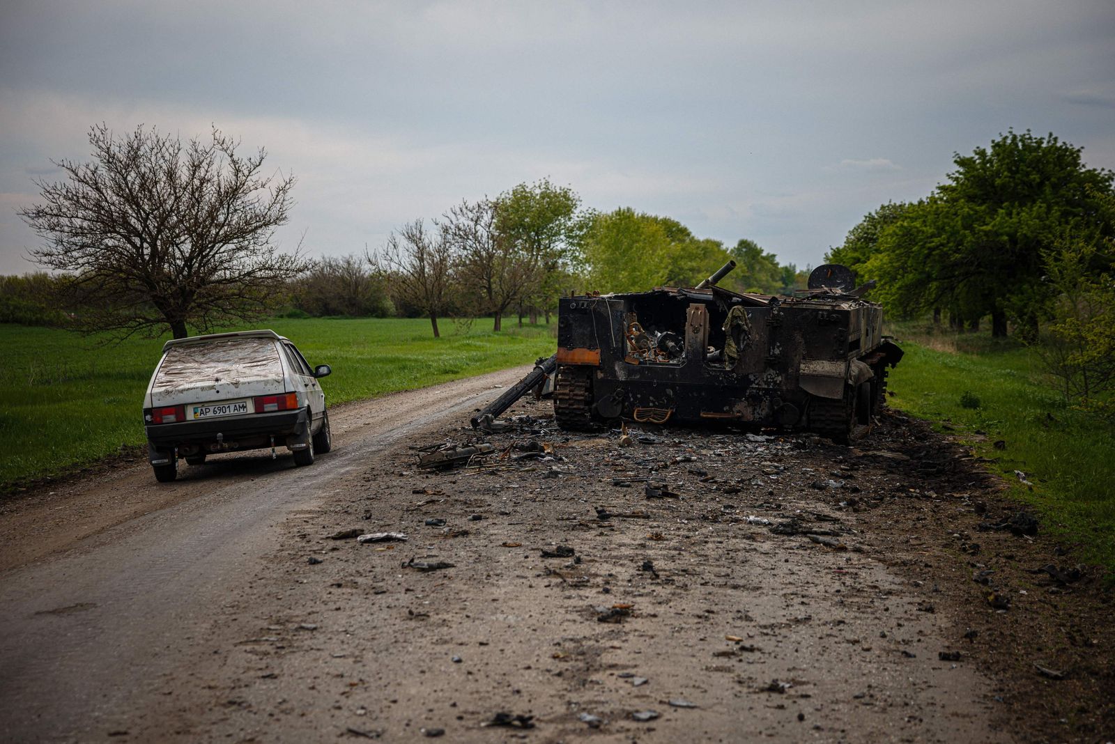 سيارة تمر بجانب مركبة قتال روسية مدمرة على طريق قرب بوكروفسك، شرق أوكرانيا. 4 مايو 2022 - AFP