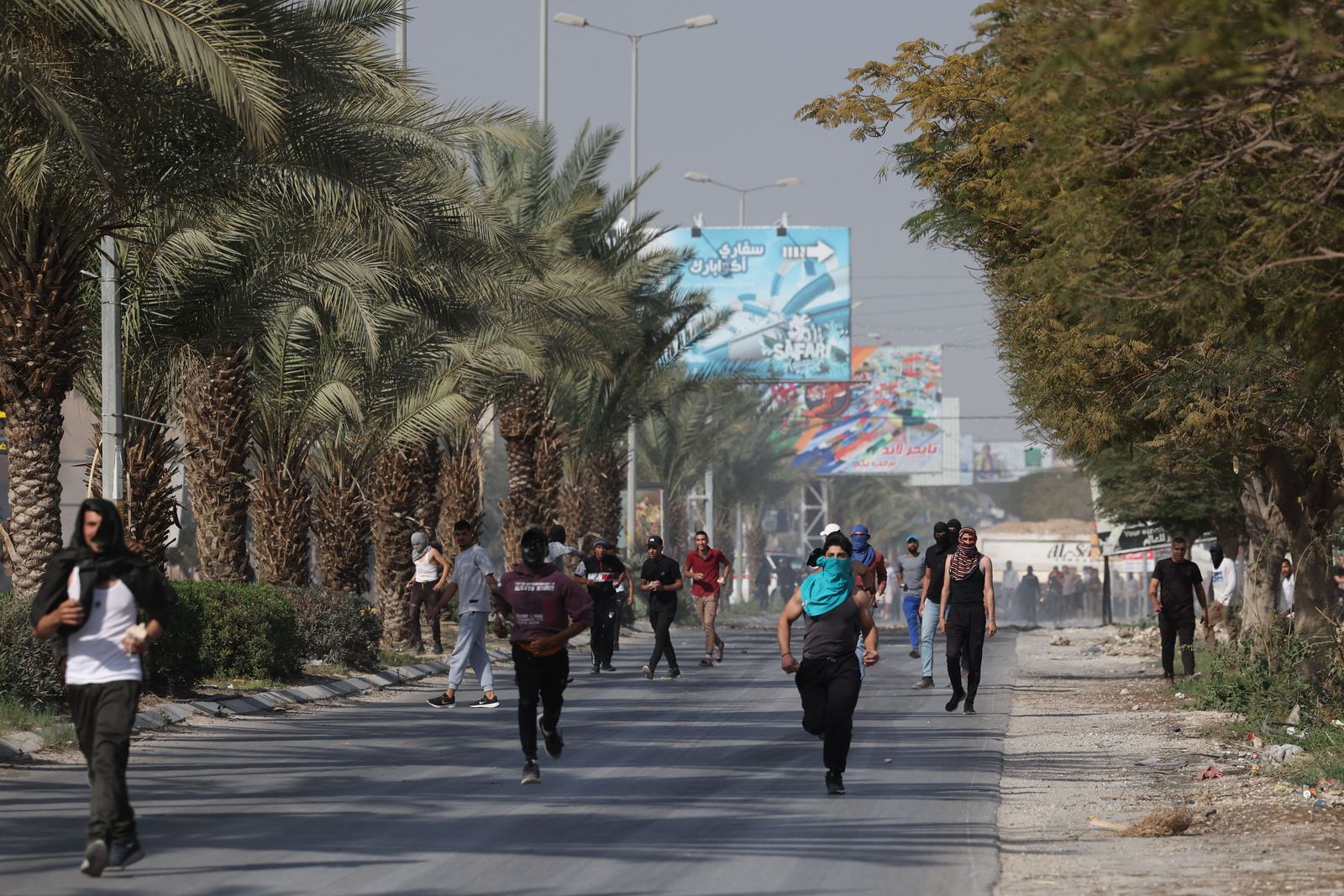 شبان فلسطينيون يركضون أثناء قيامهم بإلقاء الحجارة باتجاه الجيش الإسرائيلي خلال اقتحام لمدينة أريحا. - AFP