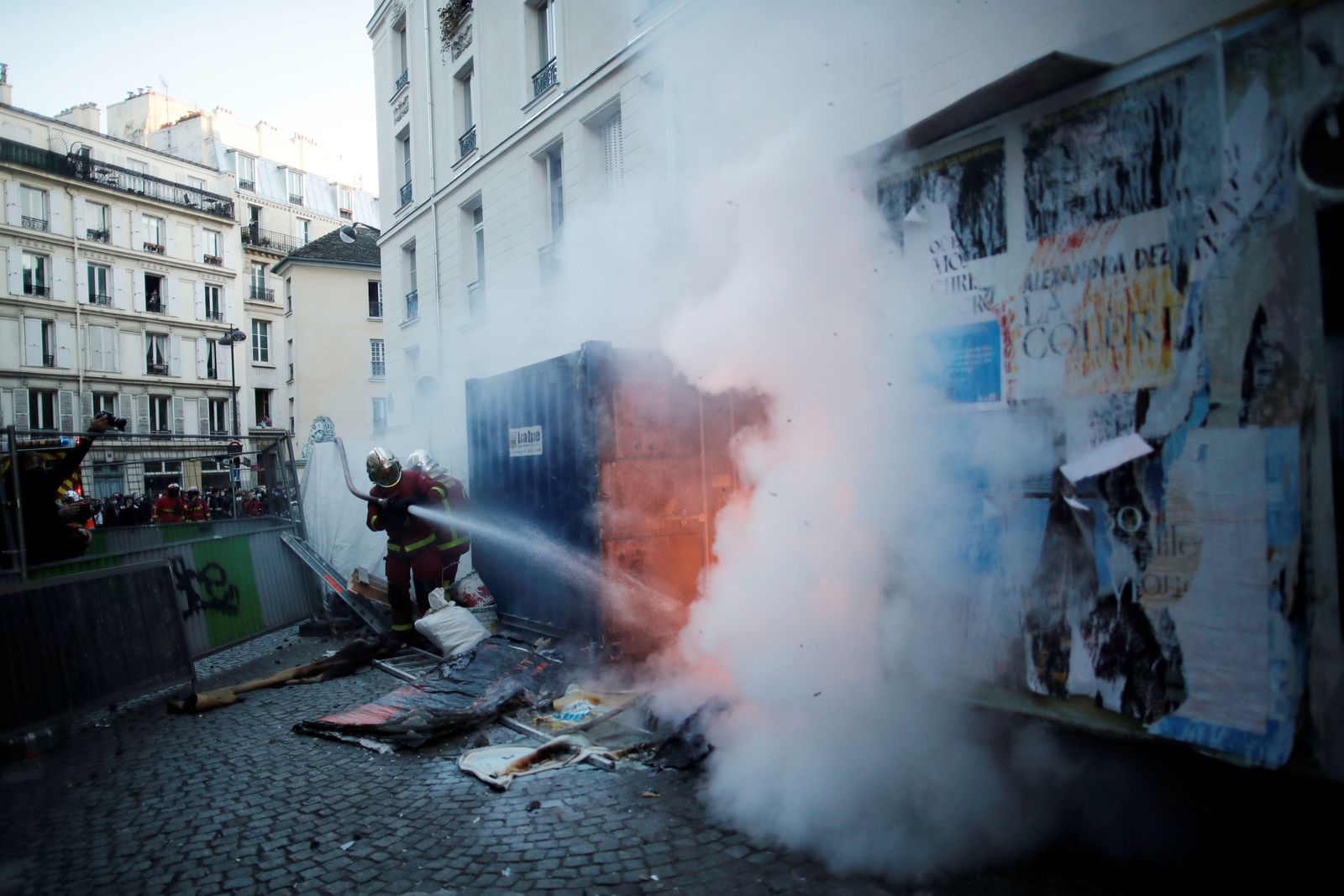 أحد عناصر الإطفاء يقوم بإخماد حريق في أحد شوارع العاصمة الفرنسية باريس على خلفية الاحتجاجات ضد مشروع قانون 