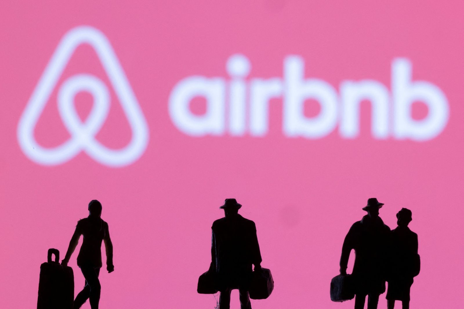 Figurines are seen in front of displayed Airbnb logo - REUTERS