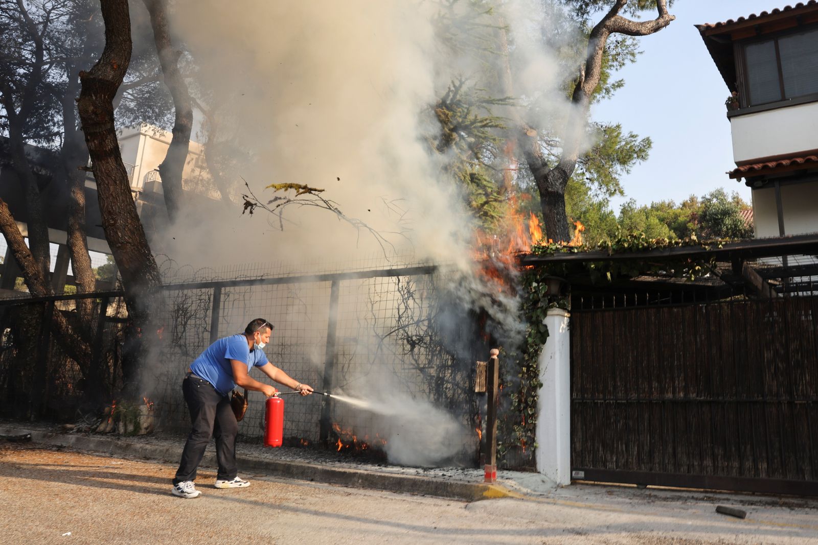 رجل يستخدم مطفأة حريق في محاولة للمساعدة في مكافحة حريق غابات في ضاحية Varympompi شمال أثينا، اليونان. 4 أغسطس 2021 - REUTERS