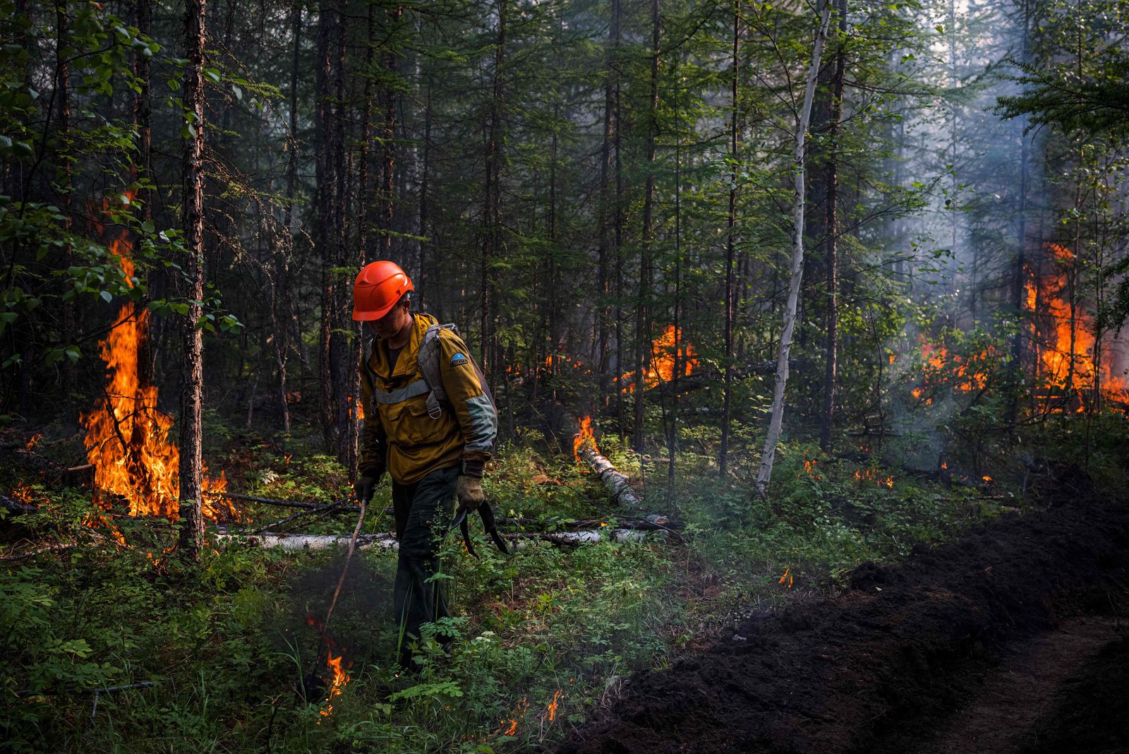 A member of Aerial Forest Protection Service brigade sets a backfire to stop a forest fire from spreading at the edge of the village of Byas-Kyuel, on July 26, 2021. - Fuelled by a June heatwave, wildfires have swept through more than 1.5 million hectares of Yakutia's swampy coniferous taiga with more than a month still to go in Siberia's annual fire season. It is the third straight year that Russia's coldest region -- with a border on the Arctic ocean -- has seen wildfires so vicious that they have nearly overwhelmed its Aerial Forest Protection Service. (Photo by Dimitar DILKOFF / AFP) - AFP