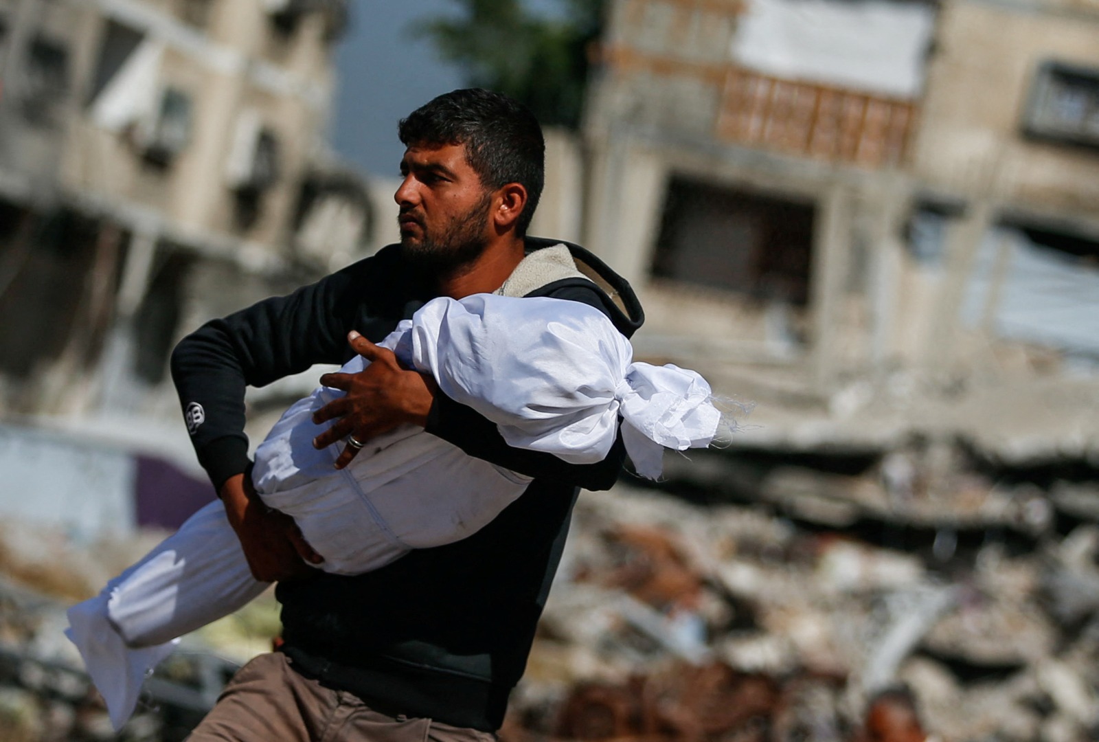 فلسطيني يحمل جثمان طفل قتلته غارات إسرائيلية في جباليا، شمال قطاع غزة. 16 مايو 2025
