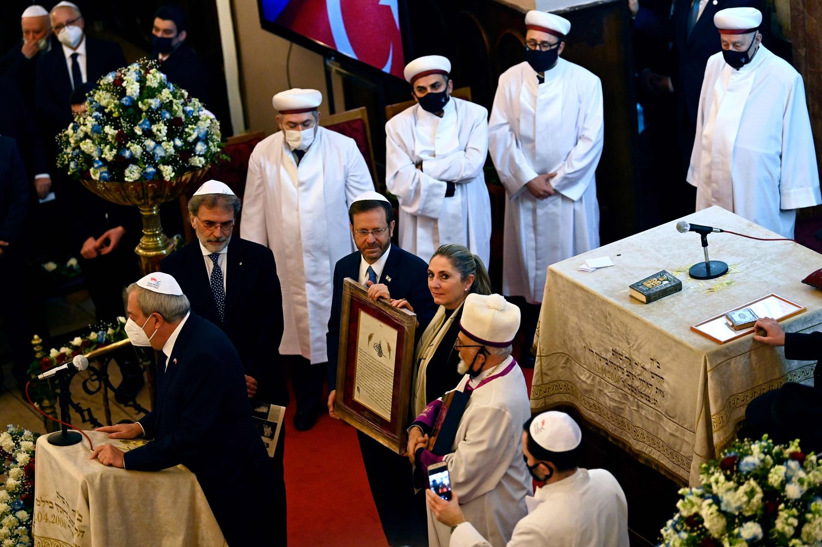 Israel's President Isaac Herzog (C-L) and his wife Michal (C-R) hold a plaque as they attend a ceremony in the Neve Shalom Synagogue in Istanbul, on March 10, 2022, during a state visit to Turkey. - Israel and Turkey proclaimed a new era in relations on March 10 following more than a decade of diplomatic rupture, as the Israeli president made a landmark visit to Ankara. (Photo by Yasin AKGUL / AFP) - AFP