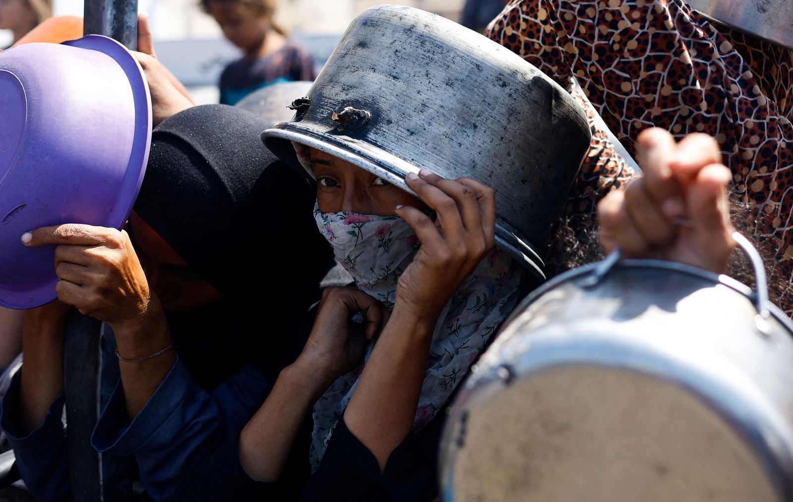A person holds a pot on their head as Palestinians wait to receive food from a charity kitchen after the global hunger monitor, Integrated Food Security Phase Classification (IPC), said that Gaza City and surrounding areas are officially suffering from famine that will likely spread, in Gaza City, August 28, 2025. REUTERS/Mahmoud Issa