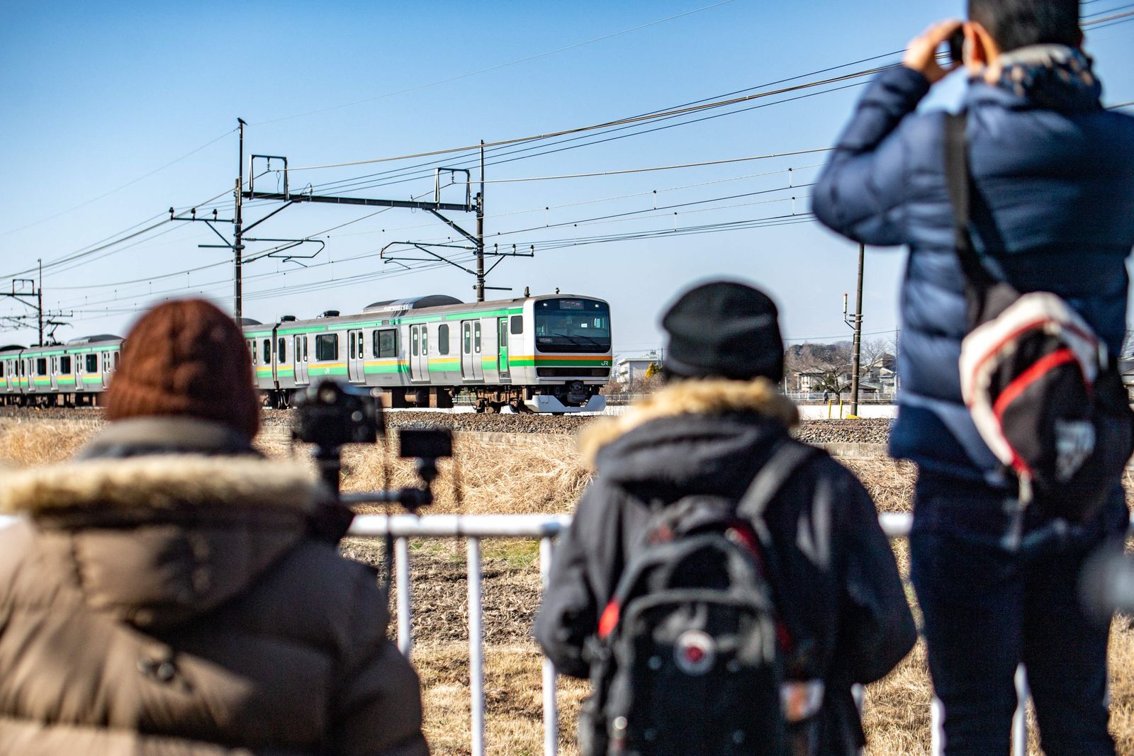 This picture taken on February 28, 2022 shows enthusiasts photographing a commuter train near a railway track in Hasuda, Saitama prefecture. - Japan's many train fans are mostly mild-mannered enthusiasts passionate about the country's famed rail system, but a small group is gaining surprising notoriety. (Photo by Philip FONG / AFP) / TO GO WITH AFP STORY JAPAN-LIFESTYLE-SOCIETY-TRANSPORT-TRAINS BY TOMOHIRO OSAKI - AFP