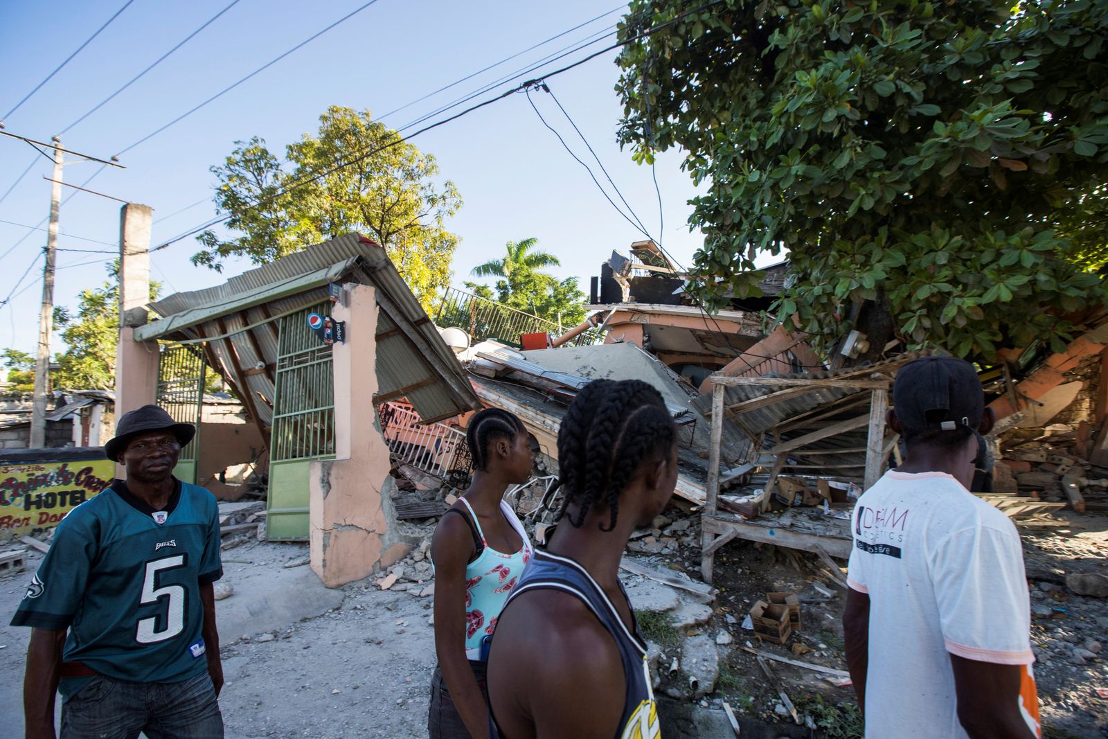  أشخاص يمشون بجوار منزل دُمر في أعقاب الزلزال، هايتي. 14 أغسطس 2021. - REUTERS
