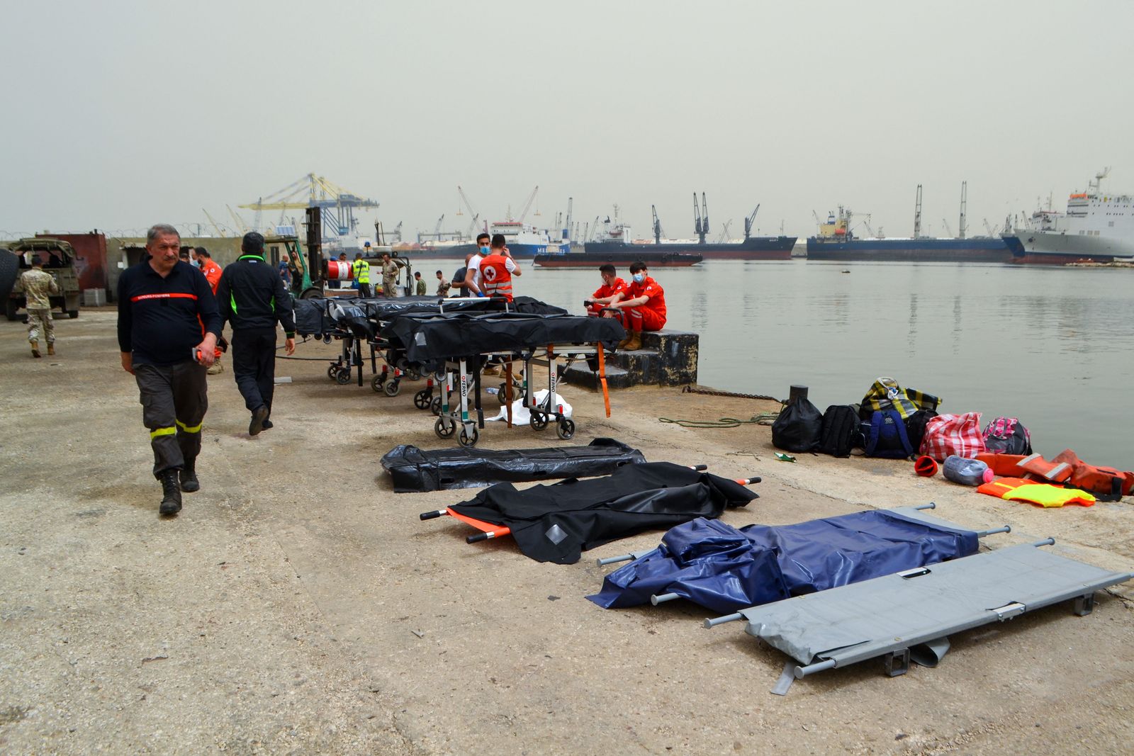Medics wait on the pier as soldiers search for survivors off the coast of the northern Lebanese city of Tripoli on April 24, 2022, after an overloaded migrant boat capsized off north Lebanon during a chase by naval forces. - At least six people died, including a little girl, and almost 50 others were rescued after an overloaded migrant boat capsized off north Lebanon during a chase by naval forces, Lebanese officials said. (Photo by AFP) - AFP