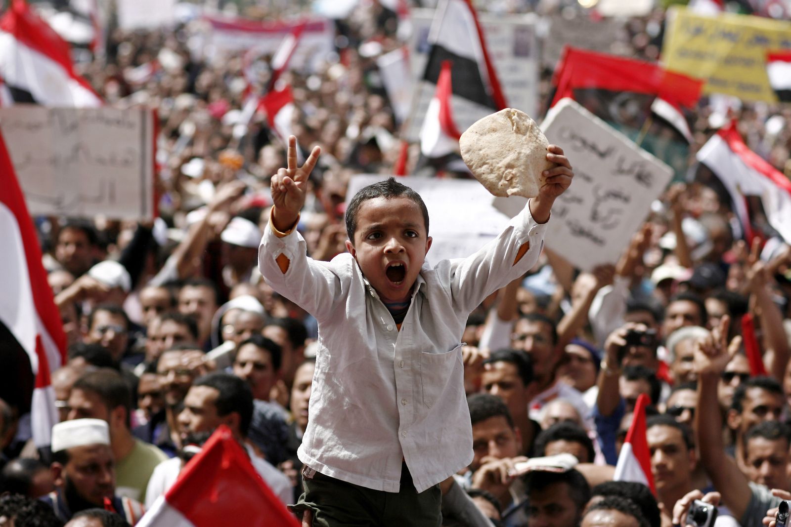 طفل يرفع رغيف خبز خلال احتجاج في ميدان التحرير بالقاهرة. 1 أبريل 2011  - AFP