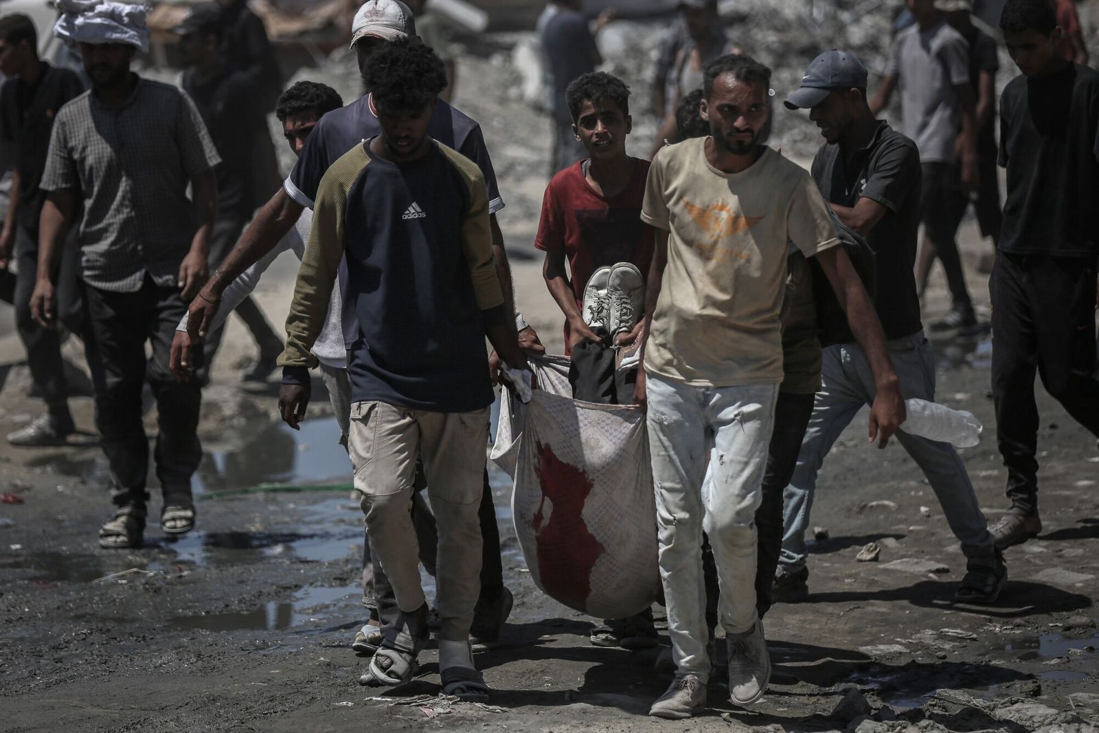 (EDITORS NOTE: Image depicts death.) Palestinians move a casualty after gathering to collect food from a humanitarian aid distribution point in Beit Lahia, northern Gaza, on Sunday, July 20, 2025. Israel shuttered traditional aid distribution channels in favor of a US-backed alternative, known as the Gaza Humanitarian Foundation (GHF), which it argued would help sideline Hamas. Photographer: Ahmad Salem/Bloomberg