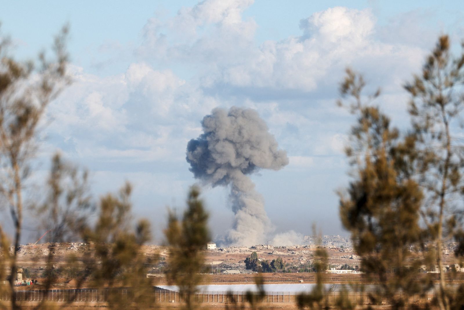 Smoke rises from an explosion in Gaza, as people attend a memorial to commemorate the two-year anniversary of the deadly October 7, 2023 attack on Israel by Hamas from Gaza, in Kibbutz Kfar Aza, as seen from southern Israel, October 7, 2025. REUTERS/Ronen Zvulun