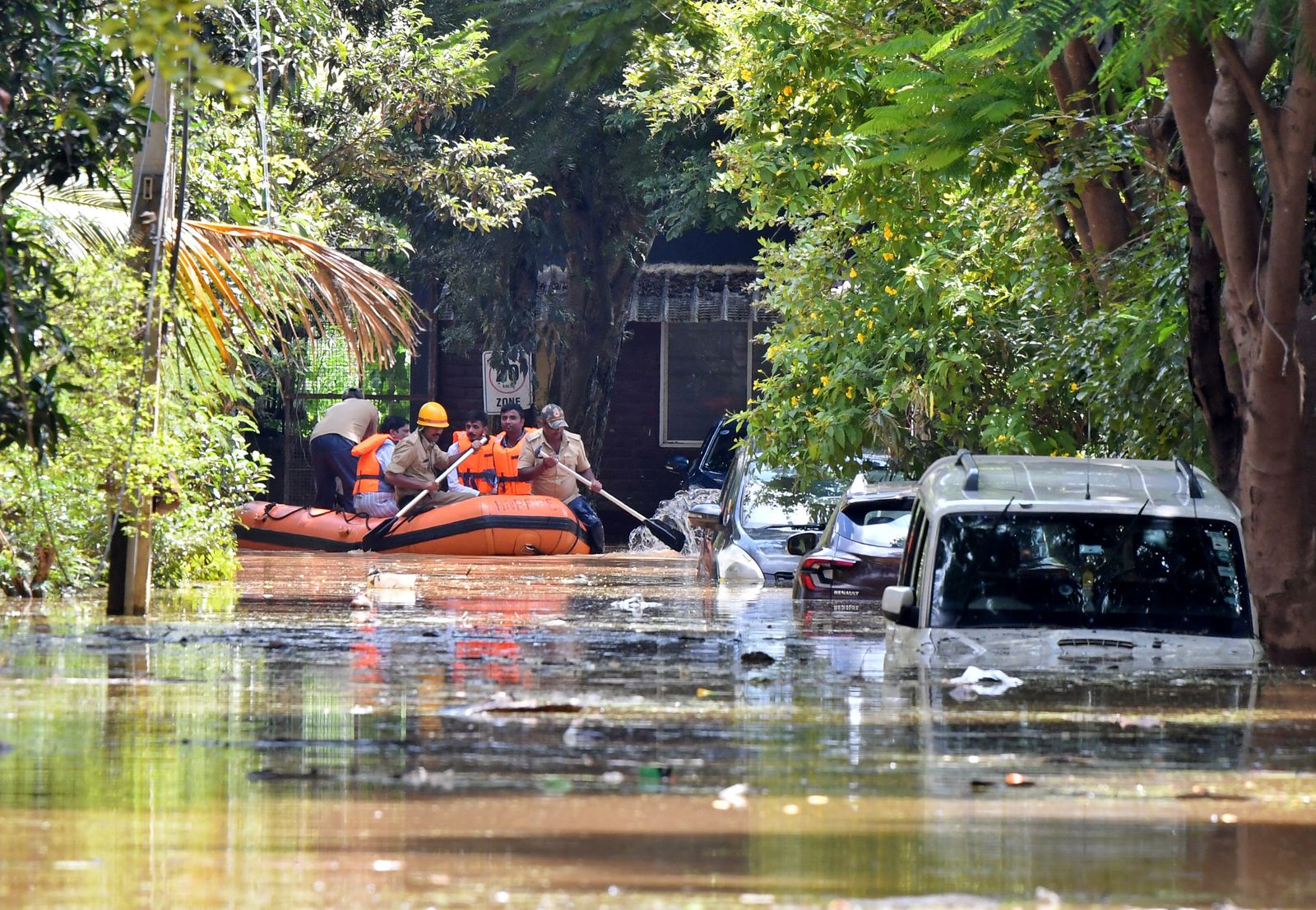 أعضاء فريق الإنقاذ يجذبون قاربهم أمام مركبات مغمورة بعد هطول أمطار غزيرة في بنجالورو - REUTERS