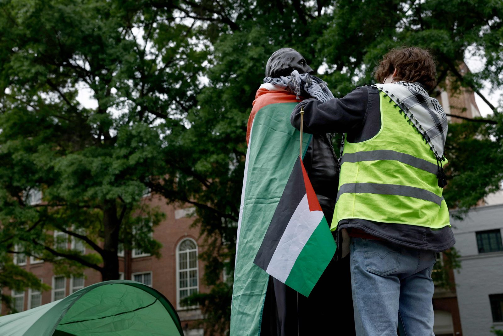 WASHINGTON, DC - APRIL 25: An activist wraps a Palestinian flag around a statue of George Washington an encampment protest at the University Yard at George Washington University April 25, 2024 in Washington, DC. Student Activists at George Washington University have joined a range of campuses across the United States who have started encampments to call on their universities to divest financial ties from Israel.   Anna Moneymaker/Getty Images/AFP (Photo by Anna Moneymaker / GETTY IMAGES NORTH AMERICA / Getty Images via AFP)