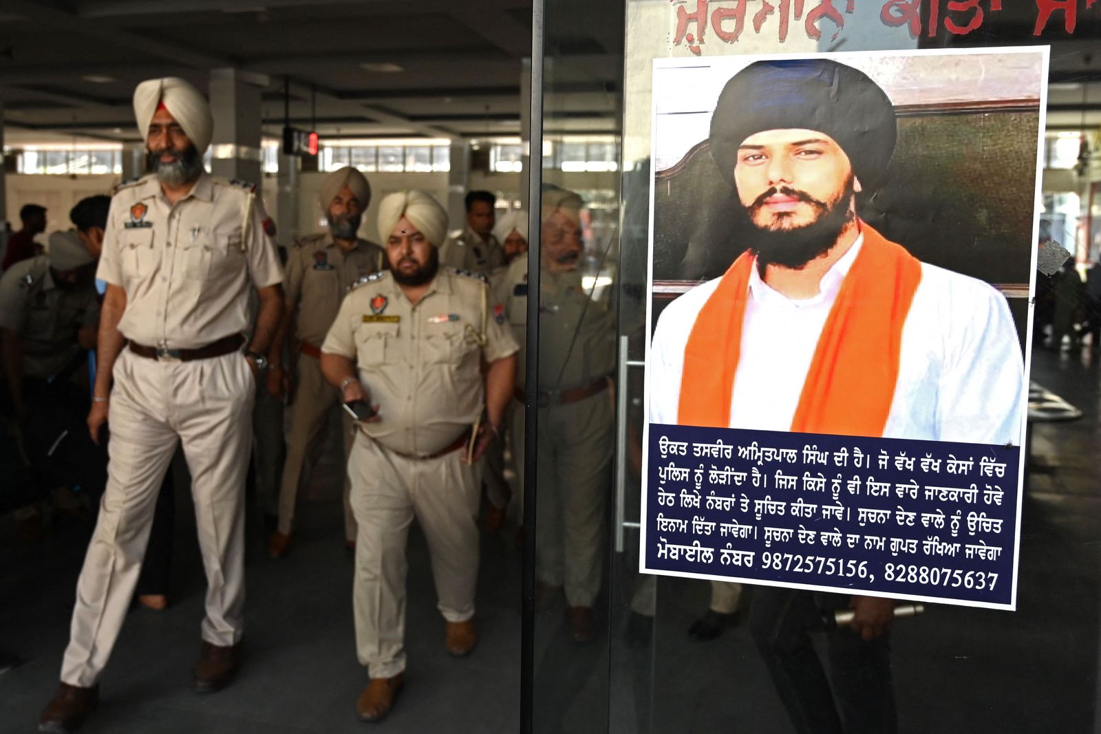 (FILES) In this file photo taken on April 13, 2023, police stick Amritpal Singh's poster at a railway station in Amritsar. - Firebrand fugitive Sikh separatist Amritpal Singh has been arrested after a massive manhunt that lasted more than a month, Indian police said on April 23. (Photo by Narinder NANU / AFP) - AFP