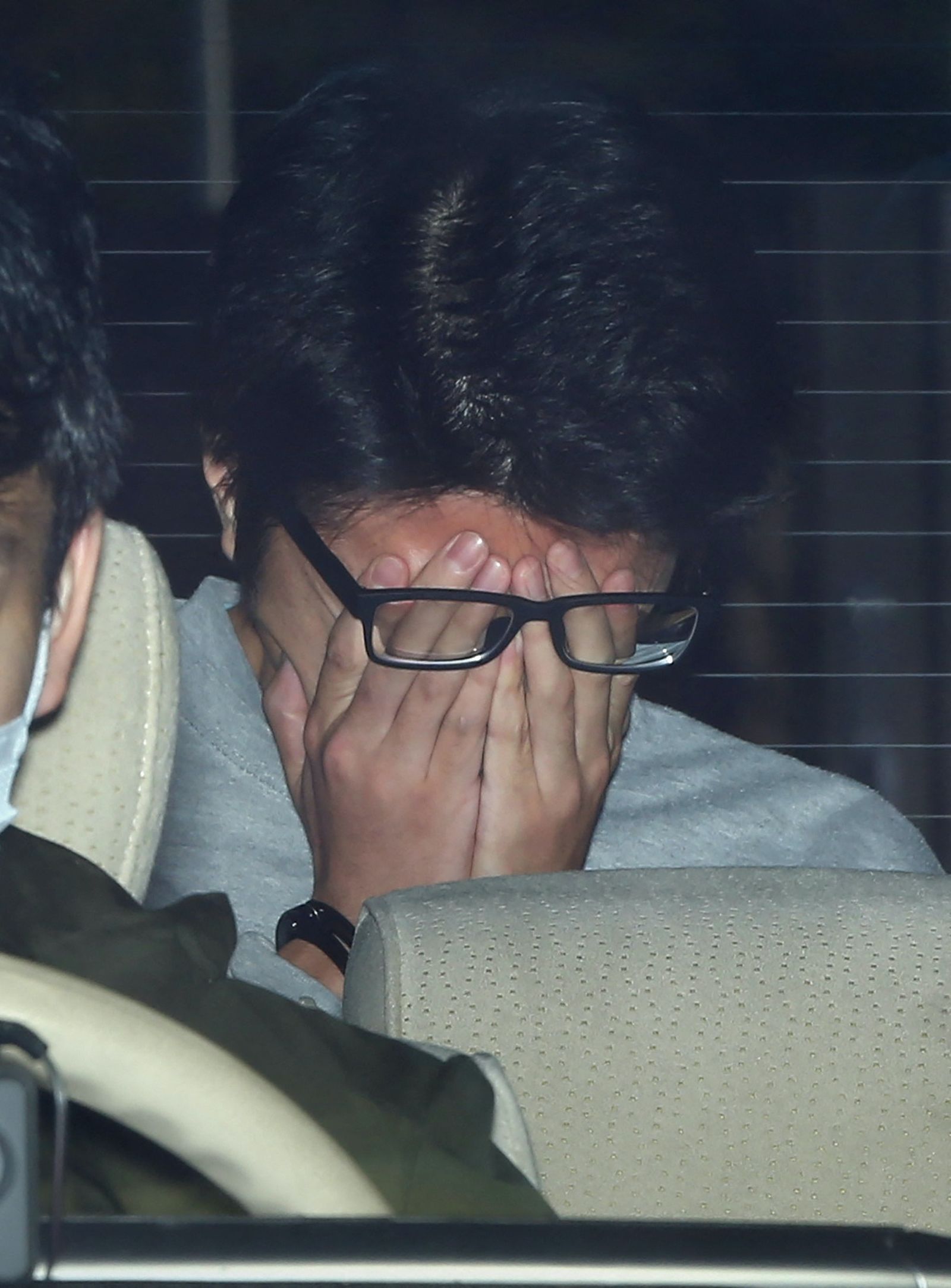 Suspect Takahiro Shiraishi covers his face with his hands as he is transported to the prosecutor's office from a police station in Tokyo on November 1, 2017. - The 27-year-old Japanese man, who was arrested after police found nine dismembered corpses rotting in his house, has confessed to killing all his victims over a two-month spree after contacting them via Twitter, media reports. (Photo by STR / JIJI PRESS / AFP) / Japan OUT - AFP