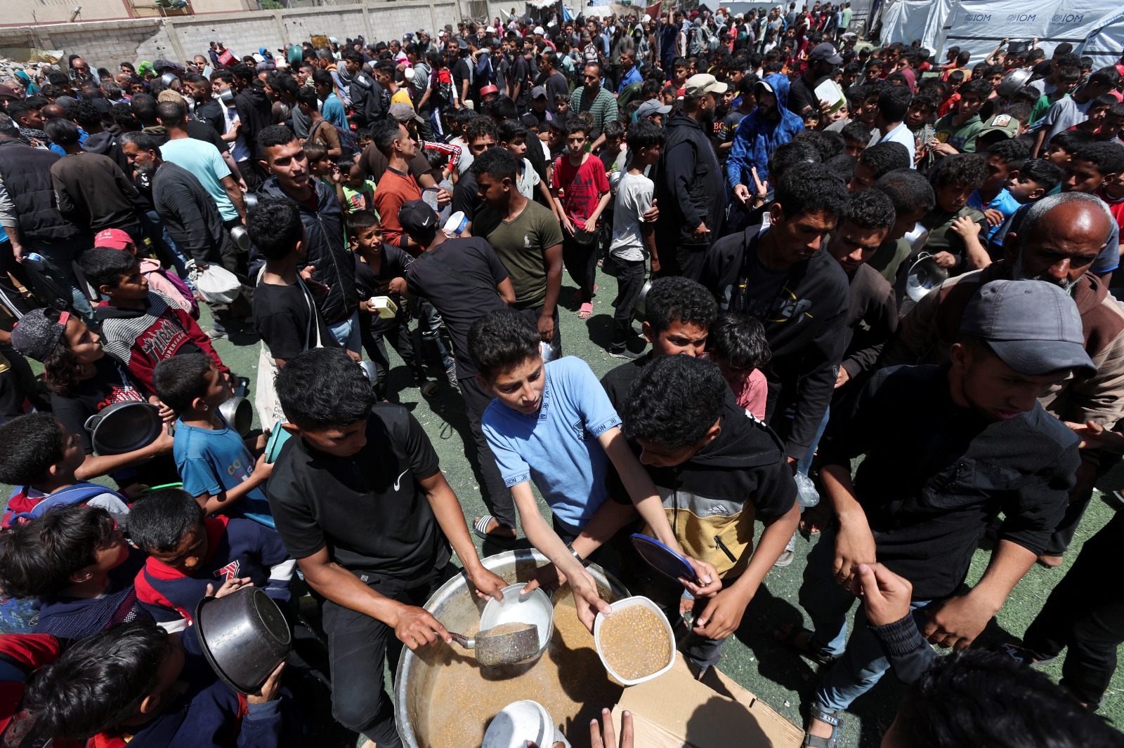 فلسطينيون ينتظرون الحصول على طعام أعدته جمعية خيرية في النصيرات وسط قطاع غزة. 28 أبريل 2025