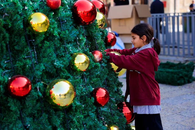 تلميذة فلسطينية تزين شجرة عيد الميلاد، بيت لحم، الضفة الغربية المحتلة، فلسطين، 24 نوفمبر 2025