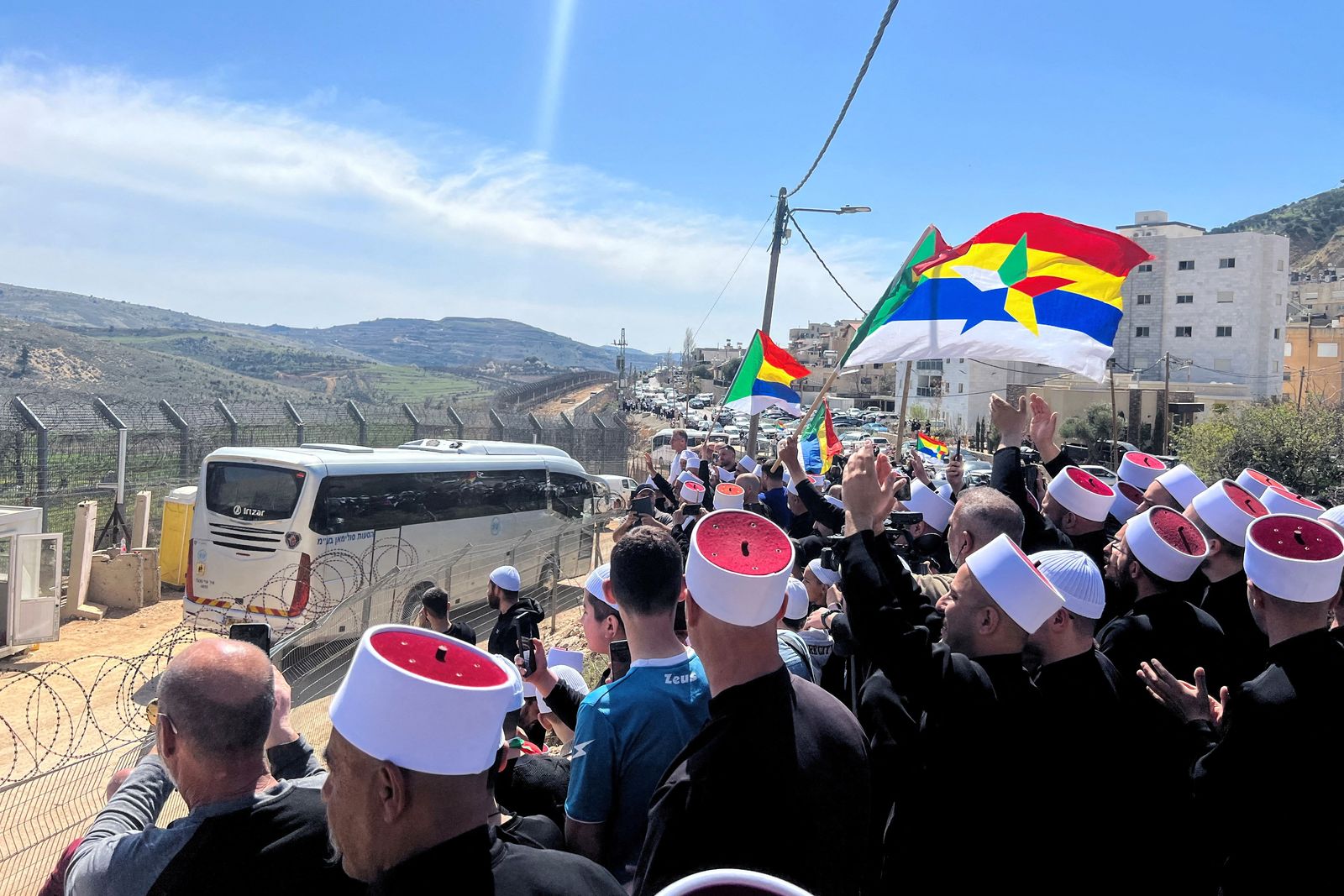 Druze people welcome buses carrying Druze delegation from Syria, as it crosses the ceasefire line between Israeli-occupied Golan Heights and Syria and enters Israel on the day of the first visit by a Druze delegation from Syria just after the 1973 war in Israel, in Majdal Shams, in the Israeli-occupied Golan Heights, March 14, 2025. REUTERS/Avi Ohayon     TPX IMAGES OF THE DAY