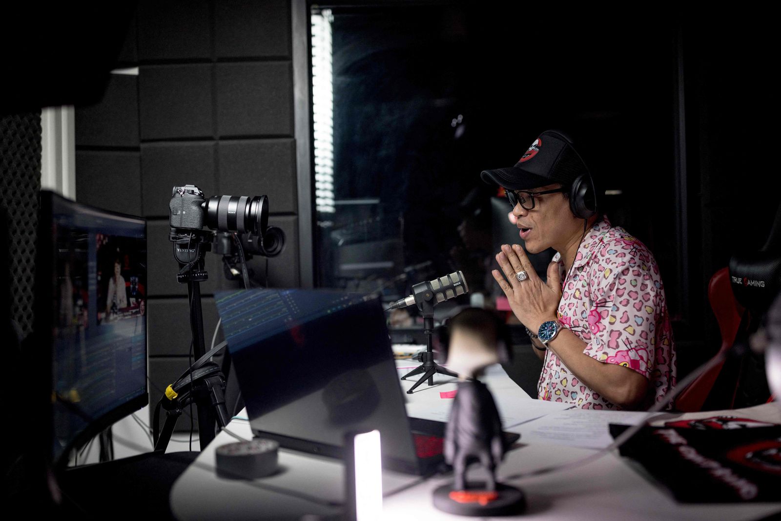 In this photo taken on March 25, 2023 Ghost Radio station host Jack Watcharaphon greets the listeners as he broadcasts live from his studio in Bangkok. - It is almost midnight, and above a semi-abandoned Bangkok shopping centre, Ghost Radio is on air. Rapid-fire comments ping across the studio's screens as thousands tune in online to hear callers describe their encounters with Thailand's supernatural. (Photo by Jack TAYLOR / AFP) / To go with 'THAILAND-RELIGION-CULTURE-PEOPLE,FOCUS' by Thanaporn PROMYAMYAI and Rose TROUP BUCHANAN - AFP