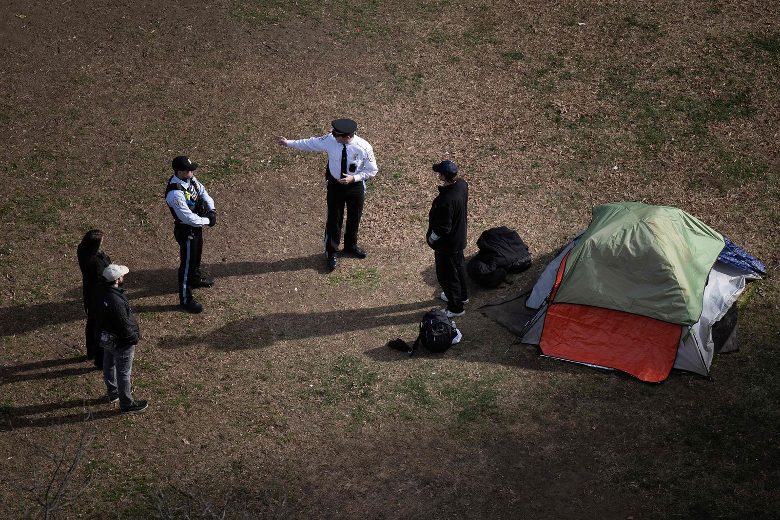 Park Police talk to a man who refused to leave after members of the US National Park Service cleared a homeless encampment from McPherson Square, two blocks from the White House in Washington, DC, on February 15, 2023. - Some 56 people live in the federal park, which is being cleared ahead of the initial April schedule due to safety concerns. (Photo by Brendan Smialowski / AFP) - AFP