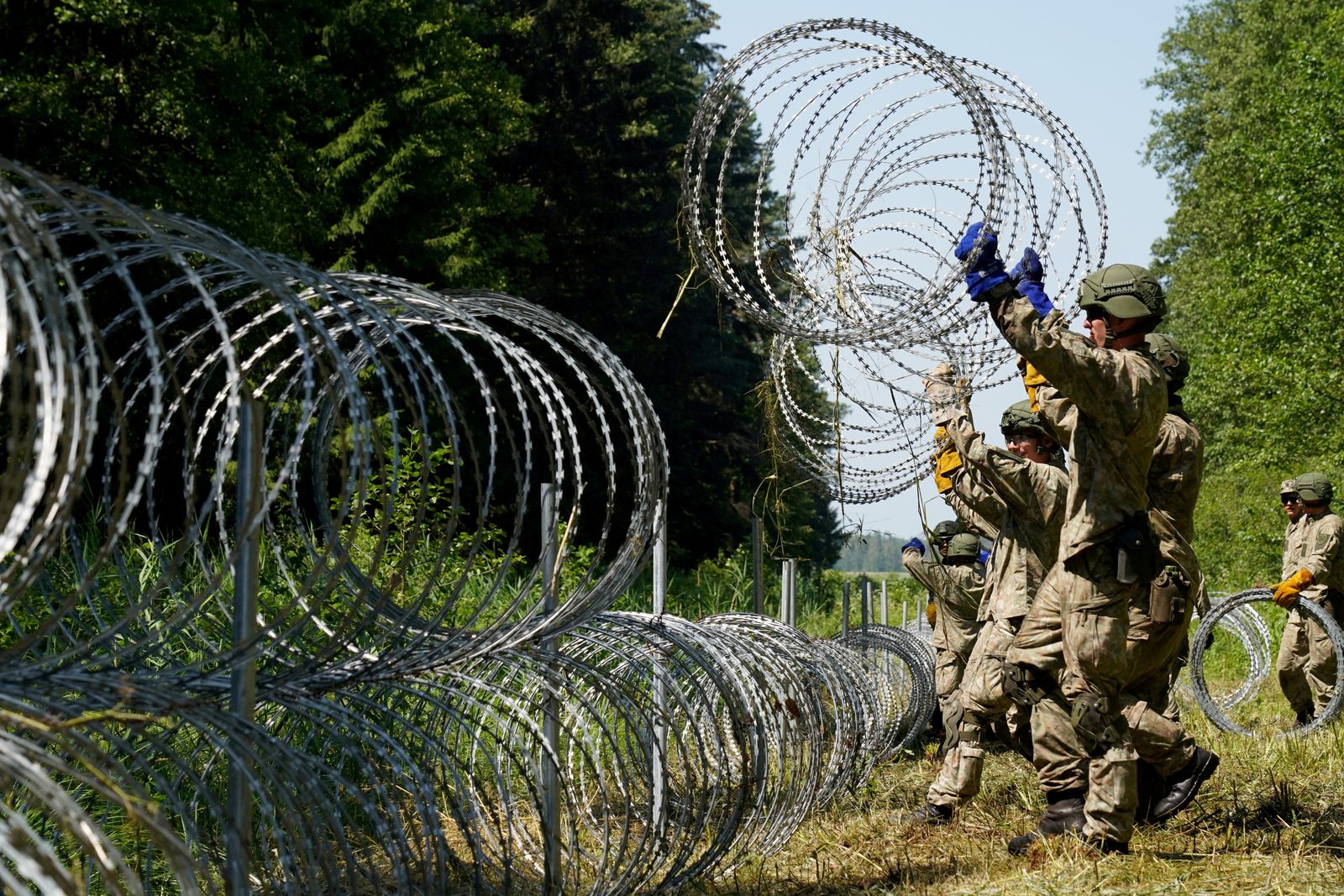 جنود ليتوانيون يثبّتون أسلاكاً شائكة على الحدود مع بيلاروسيا - 9 يوليو 2021 - REUTERS