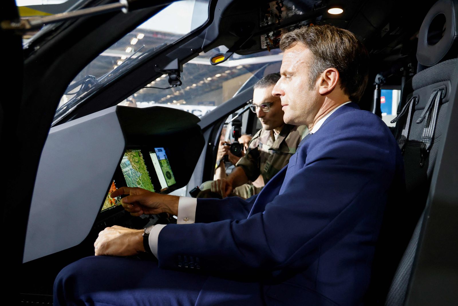 French President Emmanuel Macron looks at control monitors as he sits in the pilot's seat of an Airbus H160M Guepard helicopter during a visit to the Eurosatory land and airland defence and security trade fair, at the Paris-Nord Villepinte Exhibition Centre in Villepinte, north of Paris, on June 13, 2022. (Photo by Ludovic MARIN / various sources / AFP) - AFP