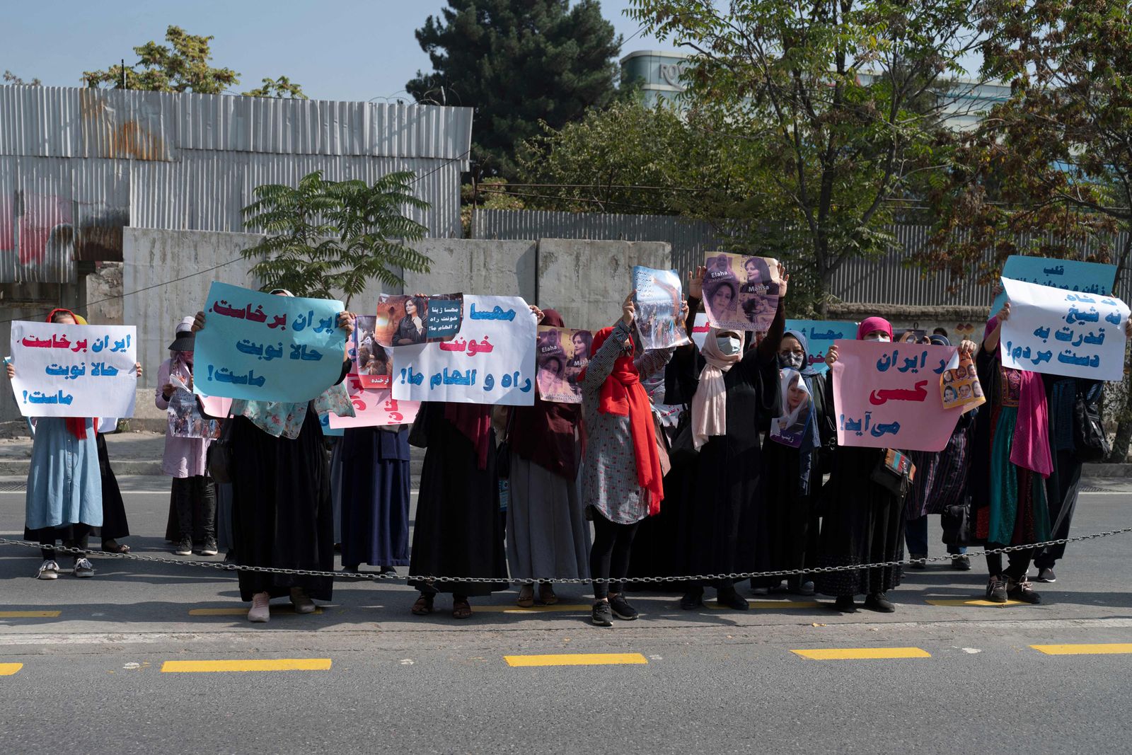 Afghan women hold placards as they take part in a protest in front of the Iranian embassy in Kabul on September 29, 2022. - Taliban forces fired shots into the air on September 29 to disperse a women's rally supporting protests that have erupted in Iran over the death of a woman in the custody of morality police. (Photo by Wakil KOHSAR / AFP) - AFP