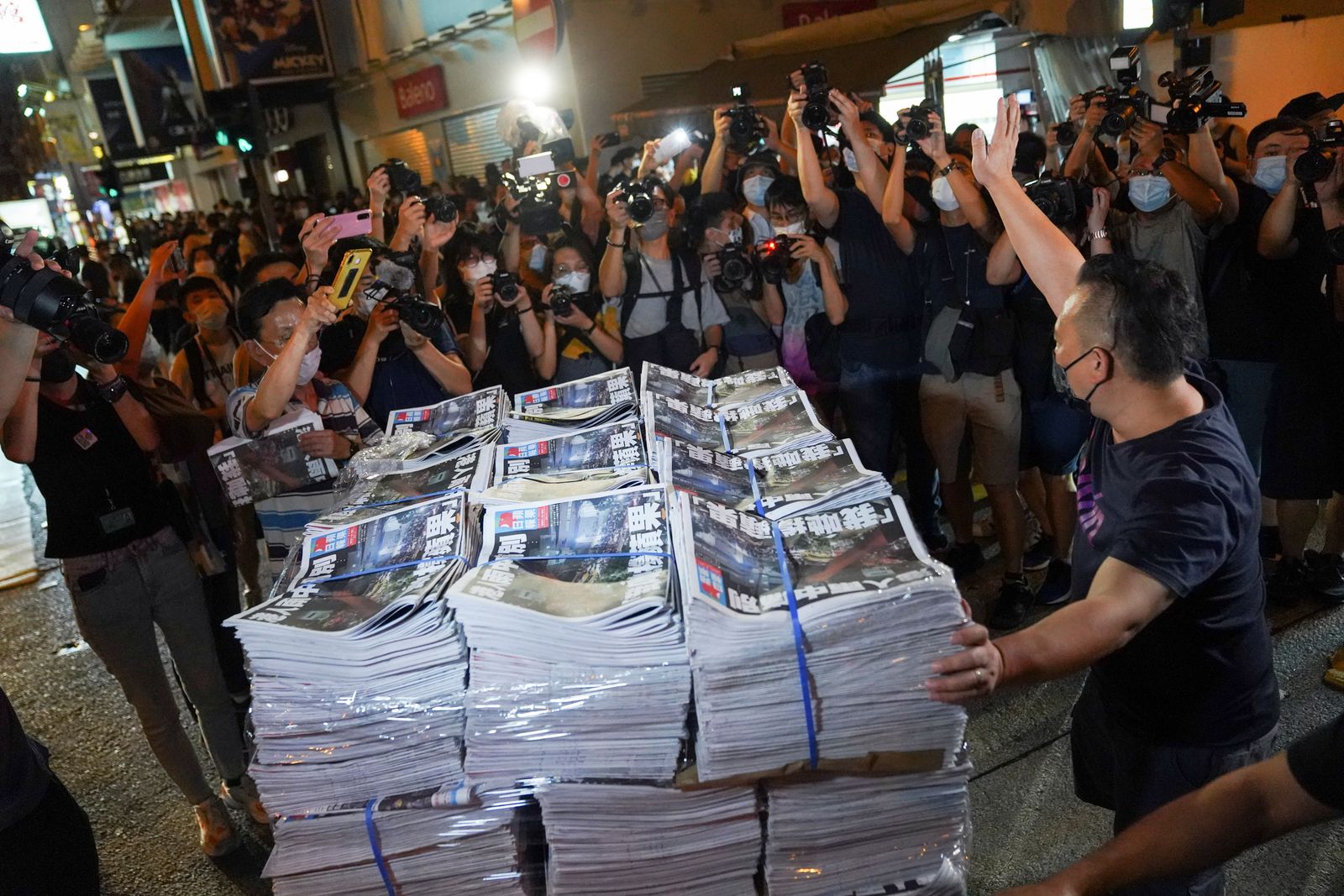 رجل يشير بإيماءاته أثناء إحضاره نسخًا من الإصدار الأخير من Apple Daily ، الذي نشرته Next Digital ، إلى كشك لبيع الصحف في هونغ كونغ ، الصين في 24 يونيو 2021 - REUTERS