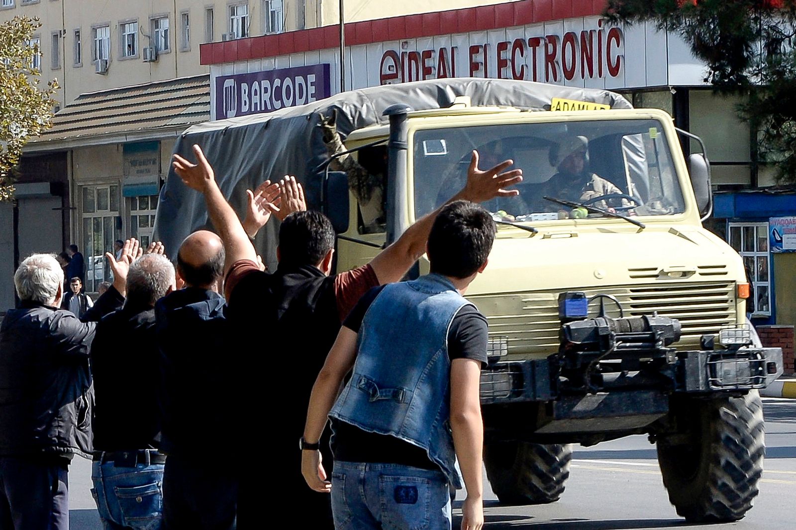 أذربيجانيون يرحبون بجنود يستقلون شاحنة عسكرية عبر بلدة بيلاجان في 2 أكتوبر 2020 - AFP