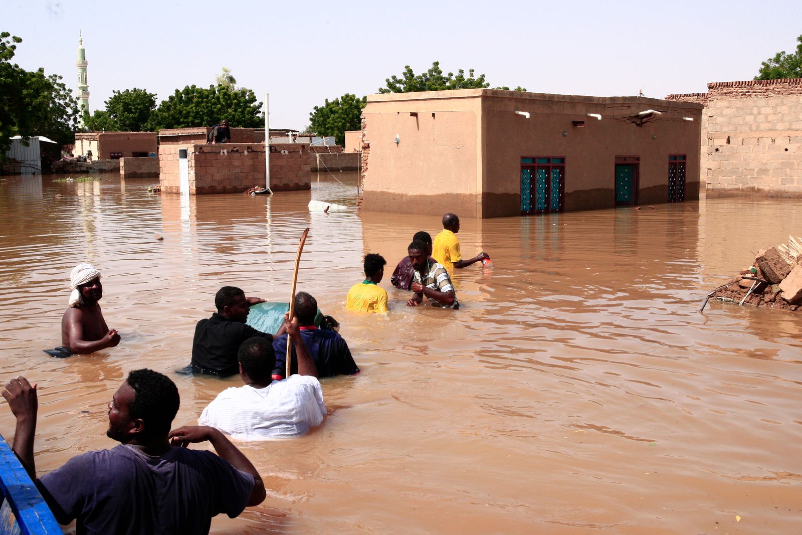أشخاص يسيرون في مياه السيول في قرية 