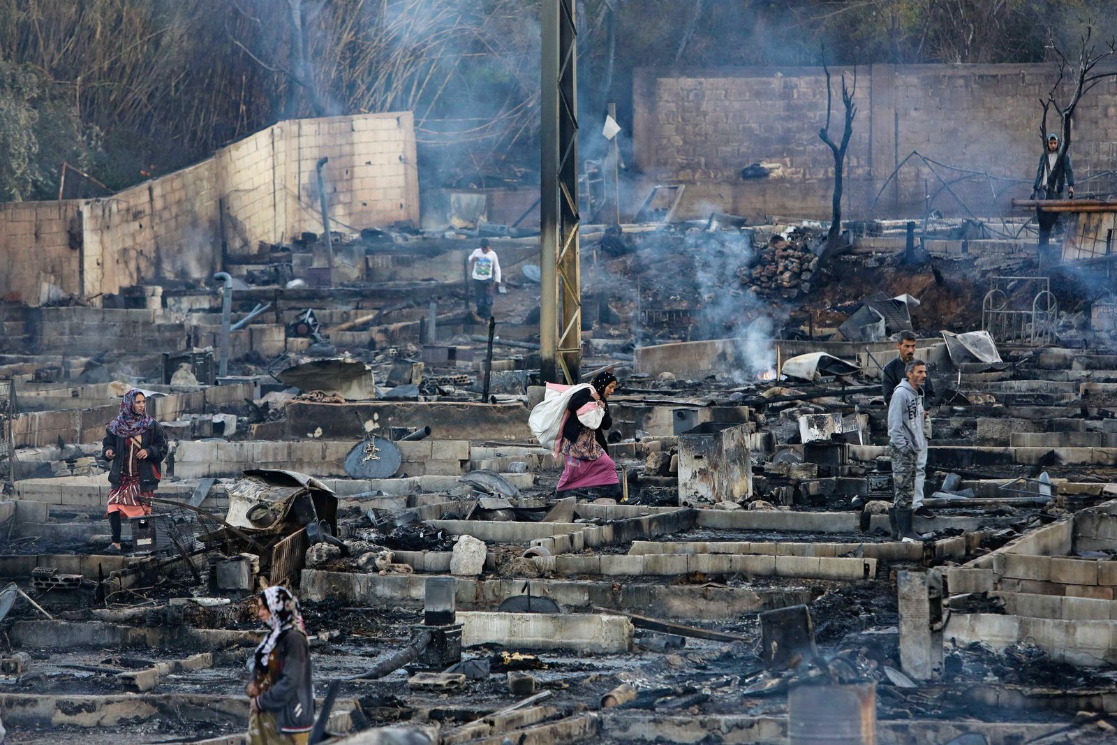 لاجئون سوريون ينتشلون ممتلكاتهم بعدما أضرمت النار في مخيماتهم في بلدة بهنين شمال لبنان - AFP
