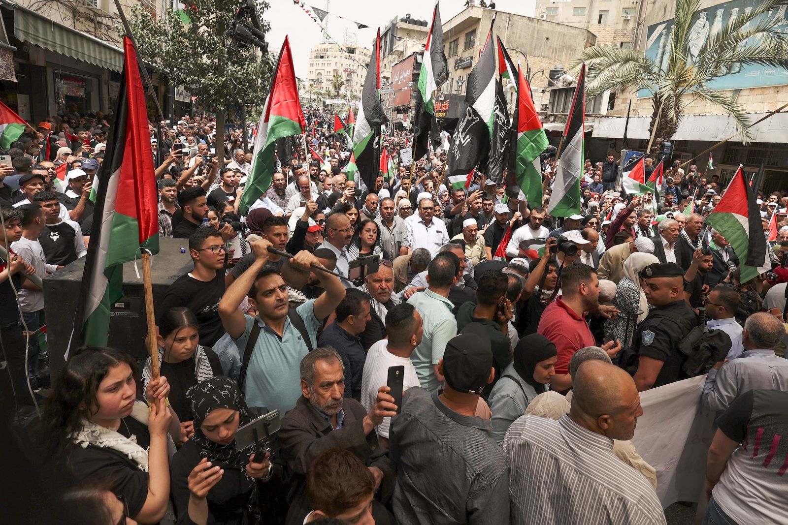 فلسطينيون يلوحون بالأعلام خلال مسيرة لإحياء ذكرى النكبة - 15 مايو 2022 - AFP