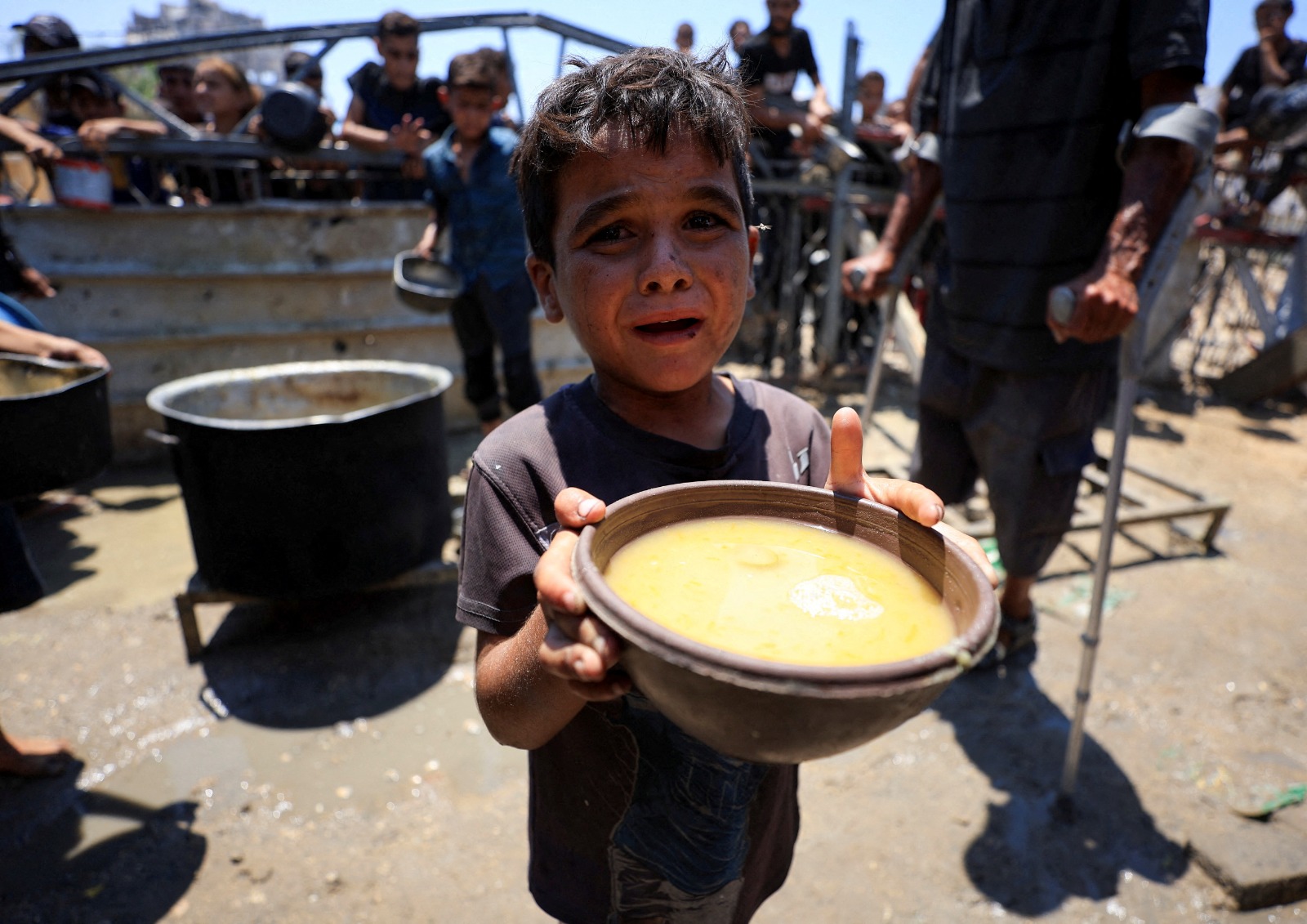 طفل فلسطيني يحمل وعاءً به طعام حصل عليه من مطبخ خيري وسط أزمة جوع في مدينة غزة شمالي القطاع. 24 يوليو 2025